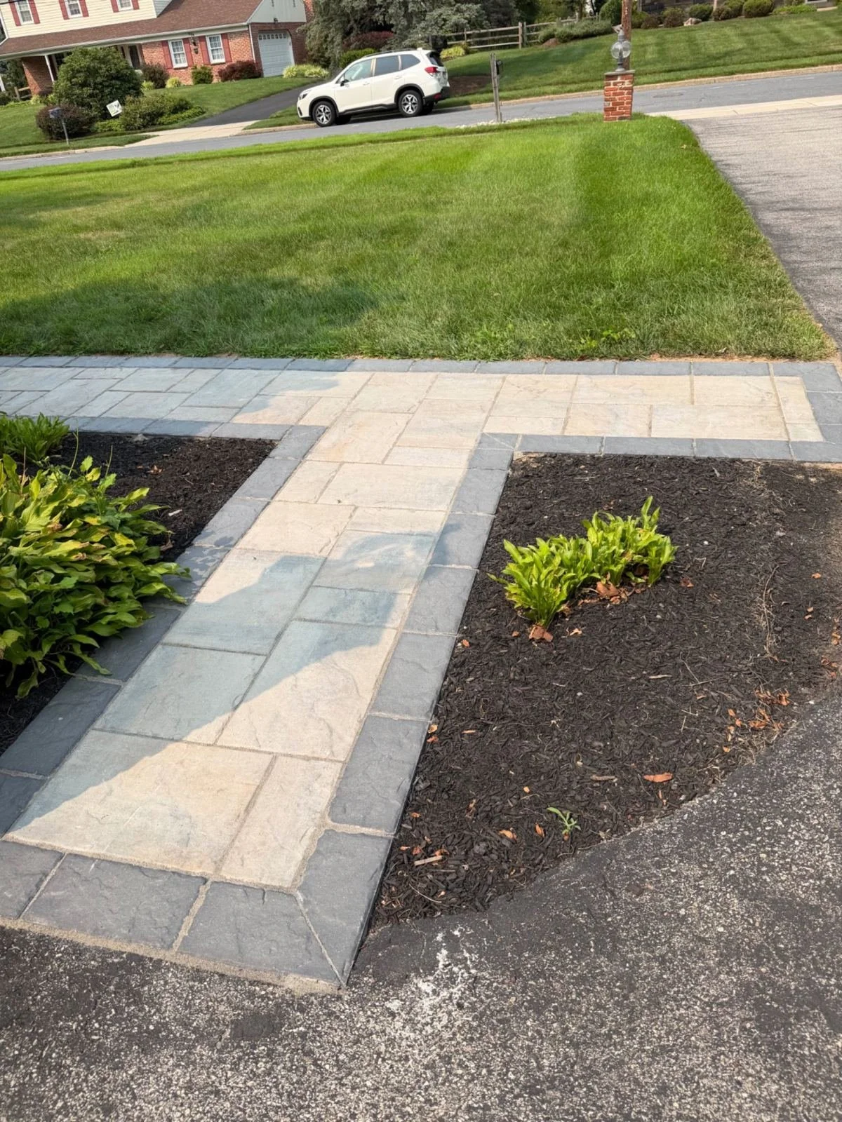Custom paver walkway with a curved layout, contrasting stone borders, and adjacent planting beds, creating an attractive transition between outdoor areas.