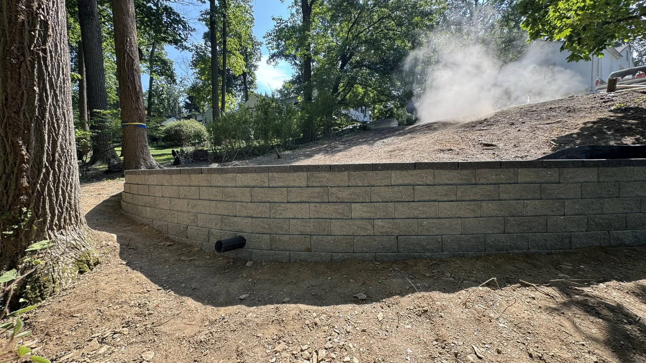 Segmental concrete block retaining wall built along a sloped residential property to retain soil, manage elevation changes, and create a defined landscape boundary with a clean, professional finish.