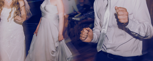 People dancing at a formal event or party, with women in white dresses and a man in a white shirt and tie.