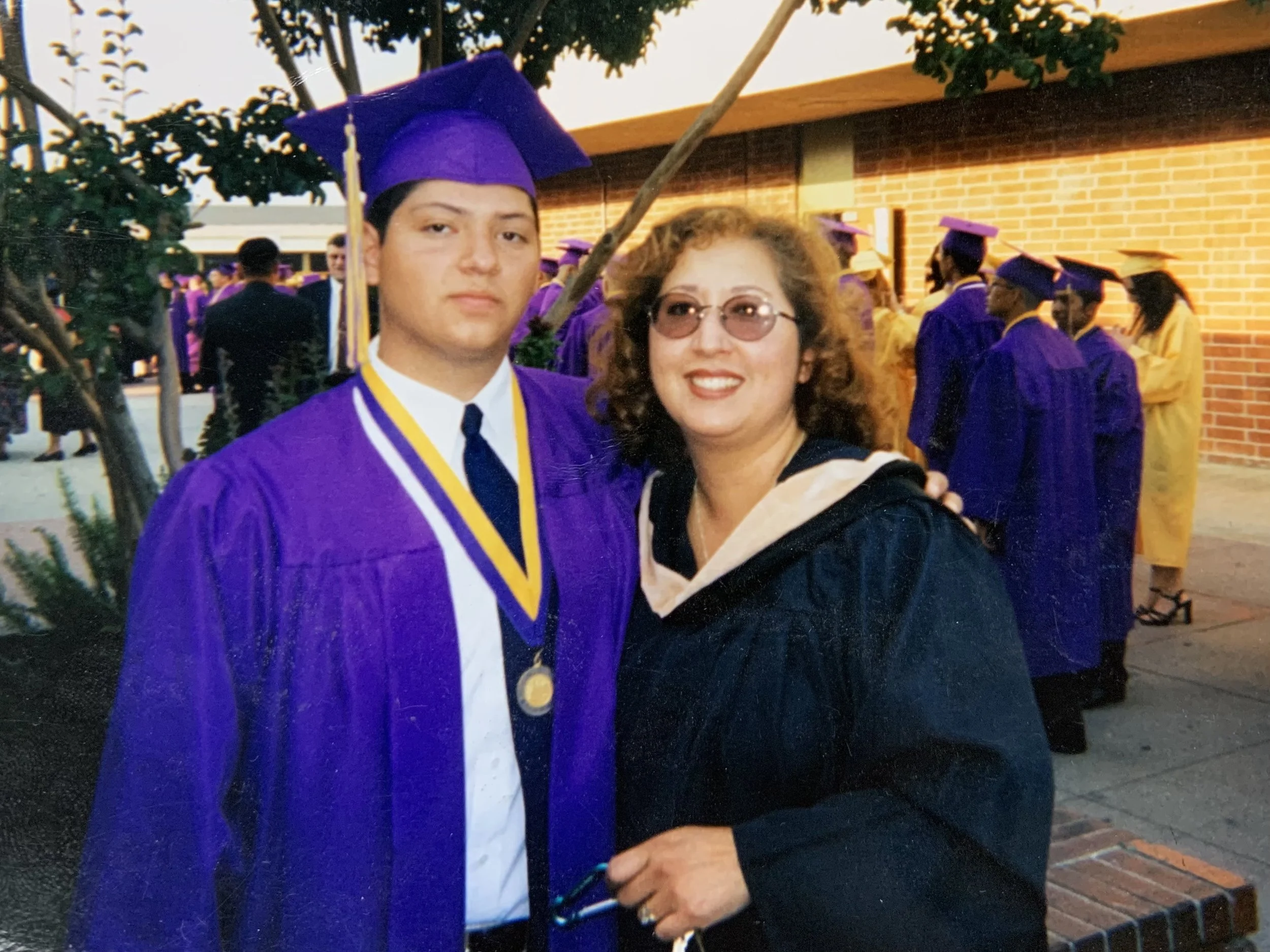 A young man in a graduation rowing standing next to a woman.