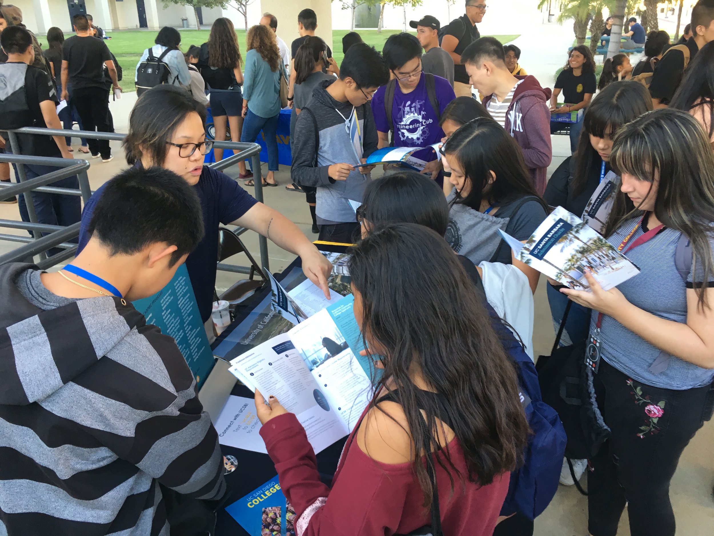 A group of students crowded around a table display.