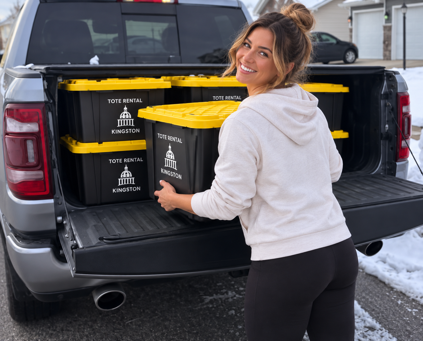 A woman loading plastic storage bins labeled 'Tote Rental Kingston' into the back of a pickup truck.