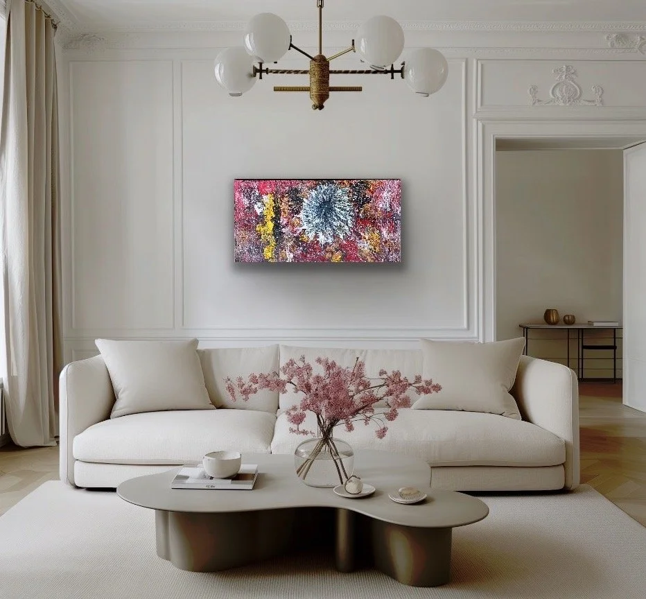 Modern living room with white sofa, abstract colorful artwork on the wall, and a black coffee table with a pink flower arrangement in a glass vase.