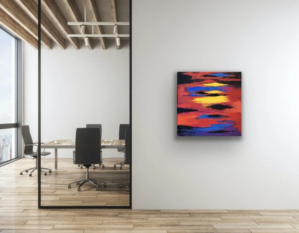 An abstract painting with red, yellow, blue, and black colors hanging on a white wall in an office space.