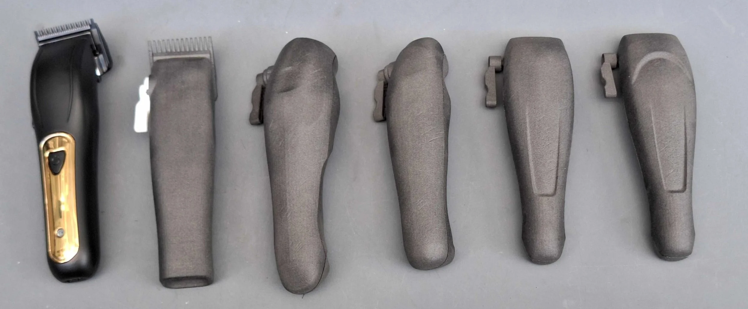 Six cosmetic or shaving razors with gray handles lined up on a gray surface, with the first razor having a black and gold design.