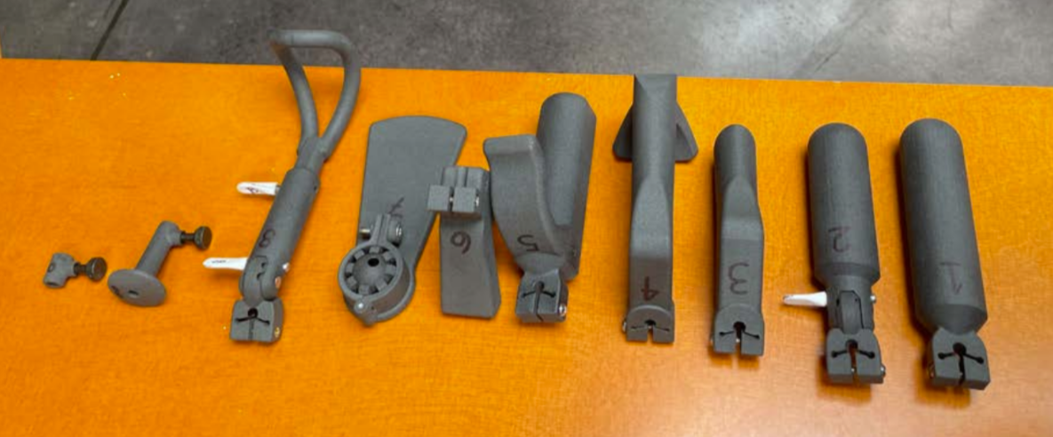 Various small metallic tools and parts laid out on an orange surface, labeled with numbers.