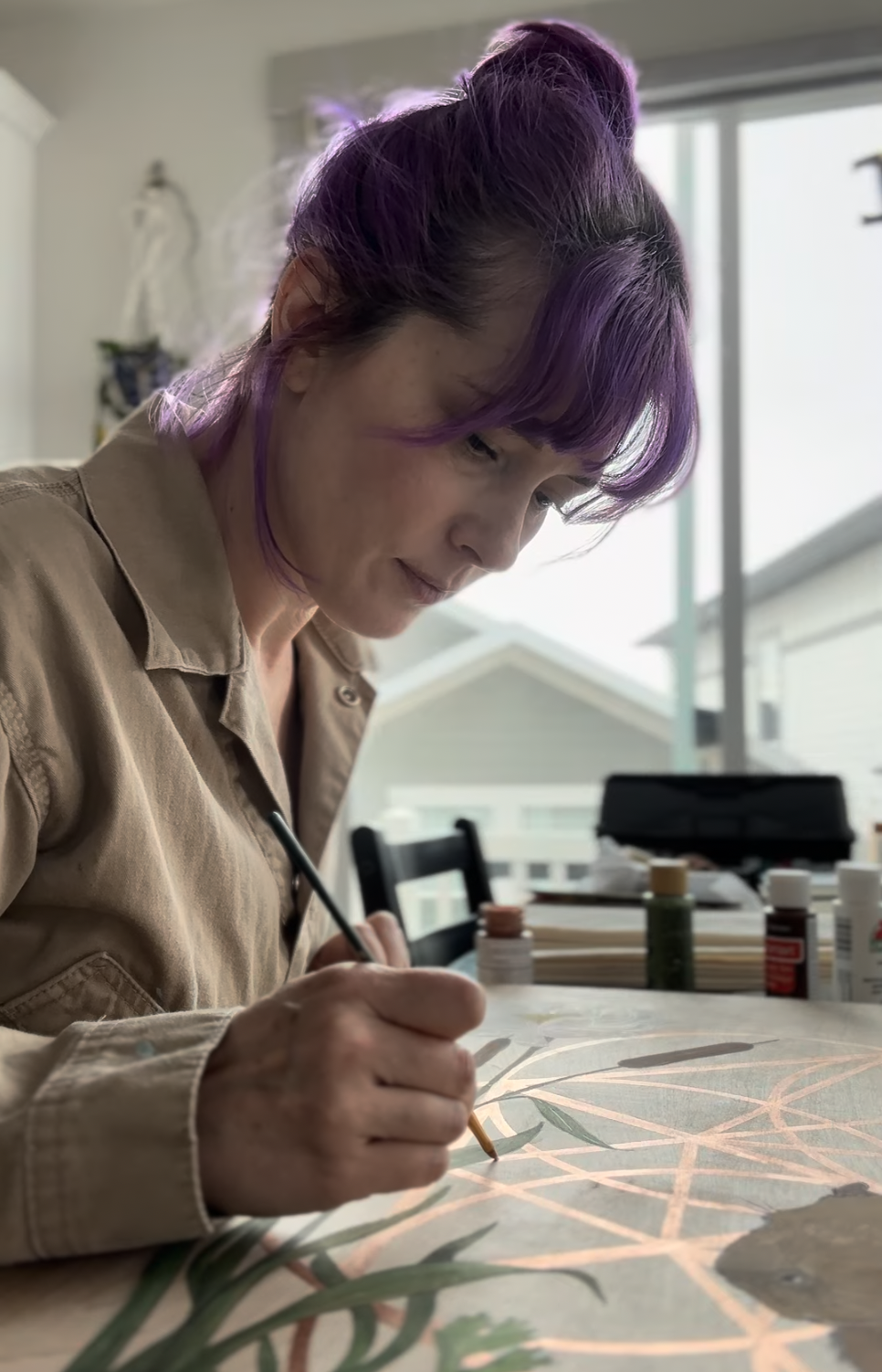 Woman with purple hair painting or drawing on a large canvas indoors.