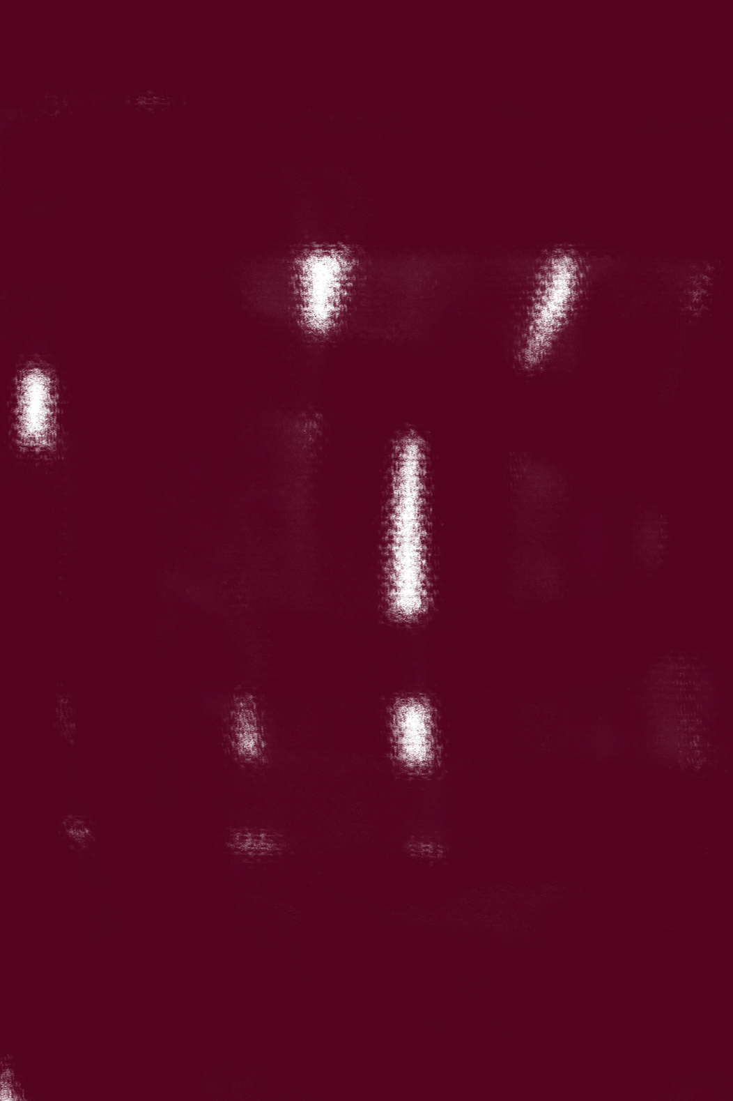 Image of a person in a dark red suit, standing in front of a maroon background.