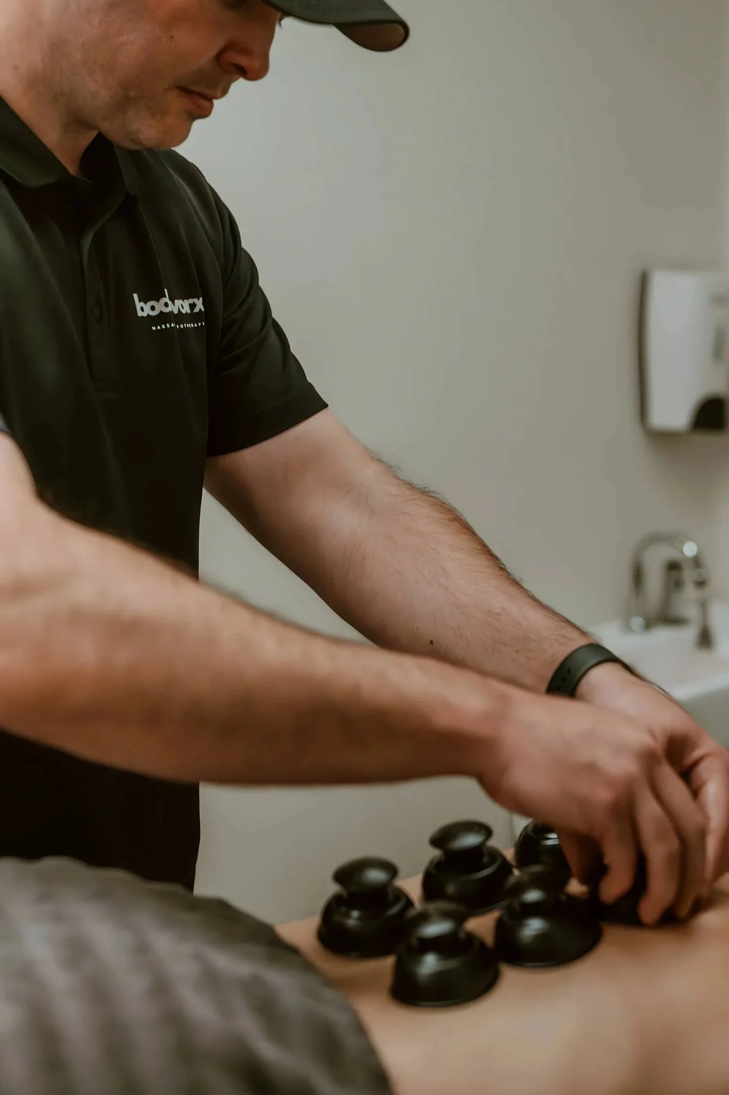 A man wearing a black polo shirt with 'bodyworx' logo is playing chess on a table.
