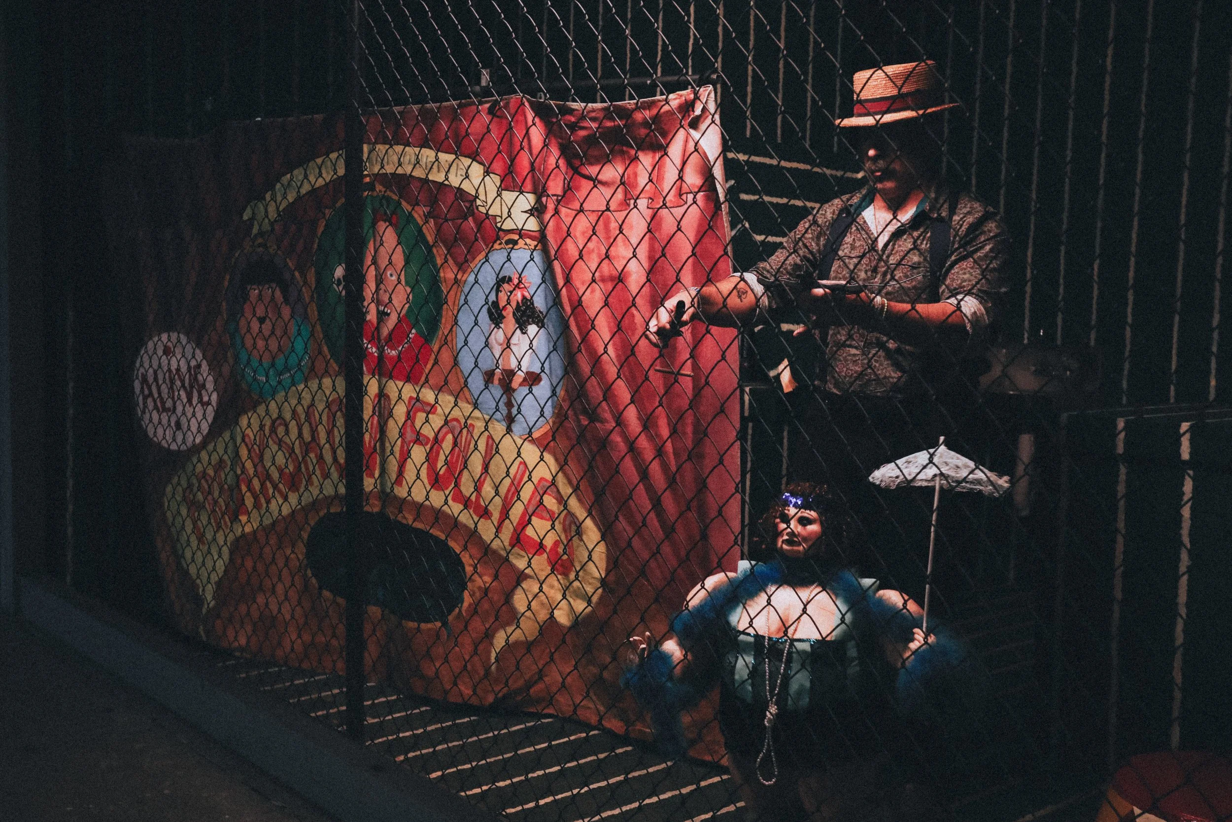 People dressed in costumes behind a wire fence, with Halloween masks and decorations, at night.