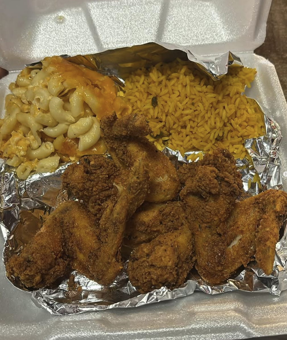 To-go container filled with fried chicken, macaroni and cheese, yellow rice, all on a foil-lined tray.