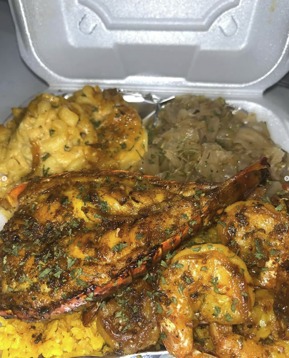 Fried shrimp with turmeric rice, cabbage, potato salad, and potato cakes in a foam takeout container