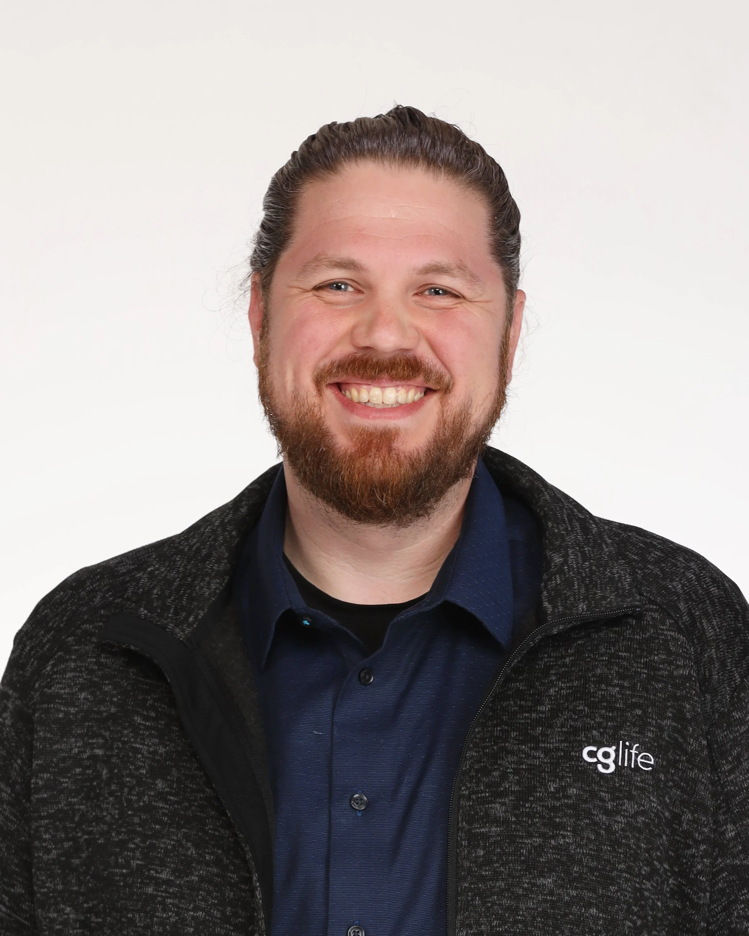 Portrait of Andrew Myers wearing a dark blue shirt and a black jacket with a small 'CG Life' logo on the right side.