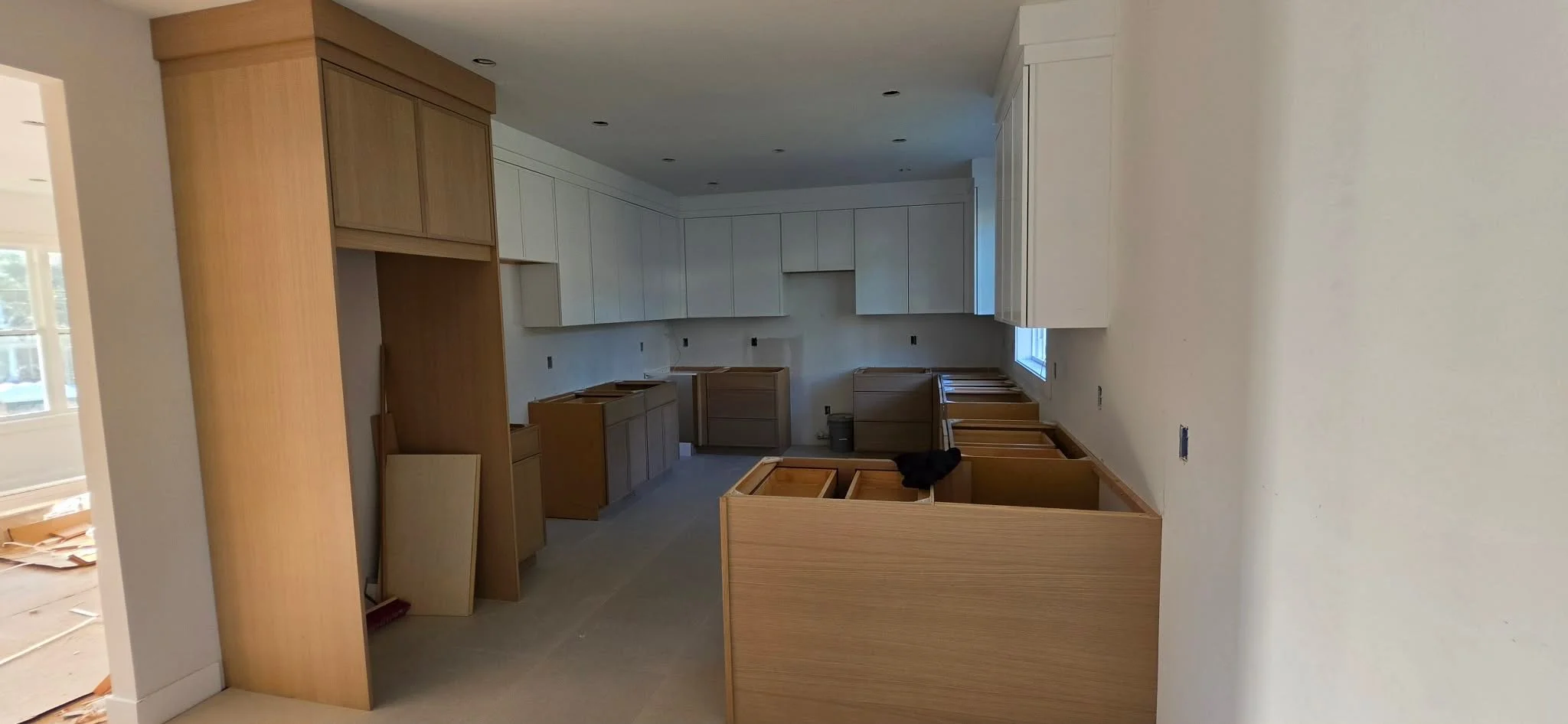 Kitchen under construction with wooden cabinets and unfinished countertops.