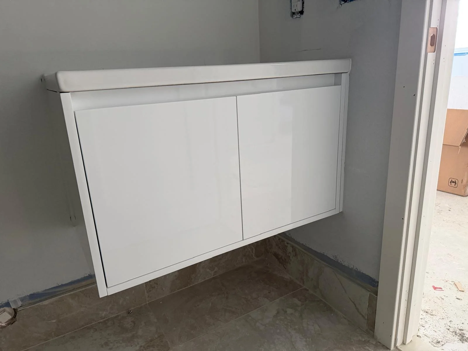 White cabinet or radiator cover mounted on a wall in a room under construction or renovation.