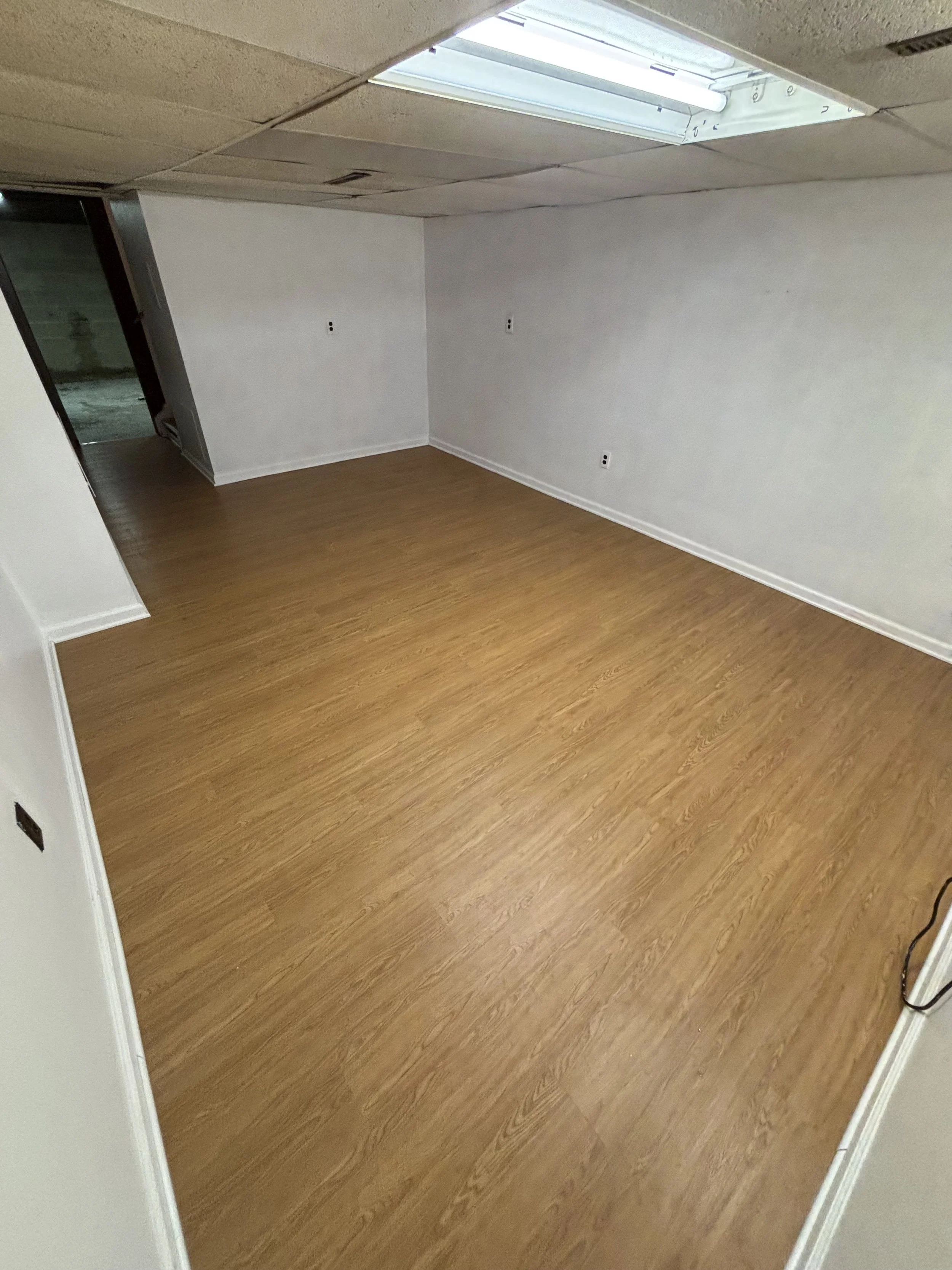 Flooring installation in a renovated room with clean finish walls and natural light.