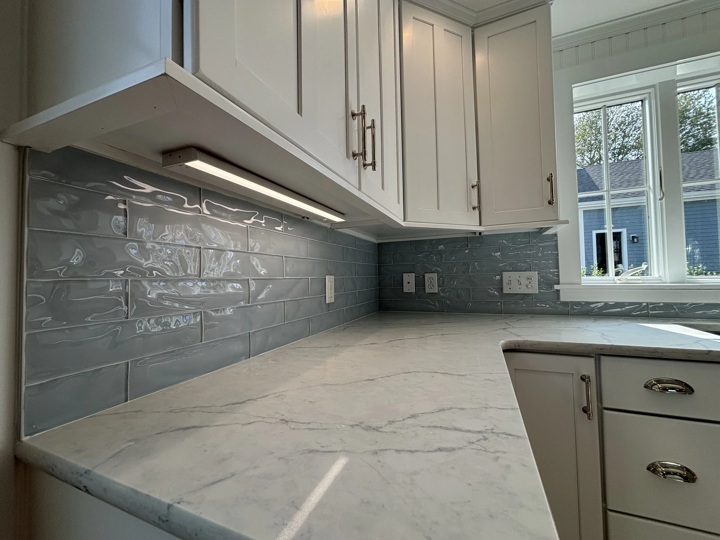 Kitchen renovation featuring white cabinets, stone countertop, backsplash, and modern finishes.