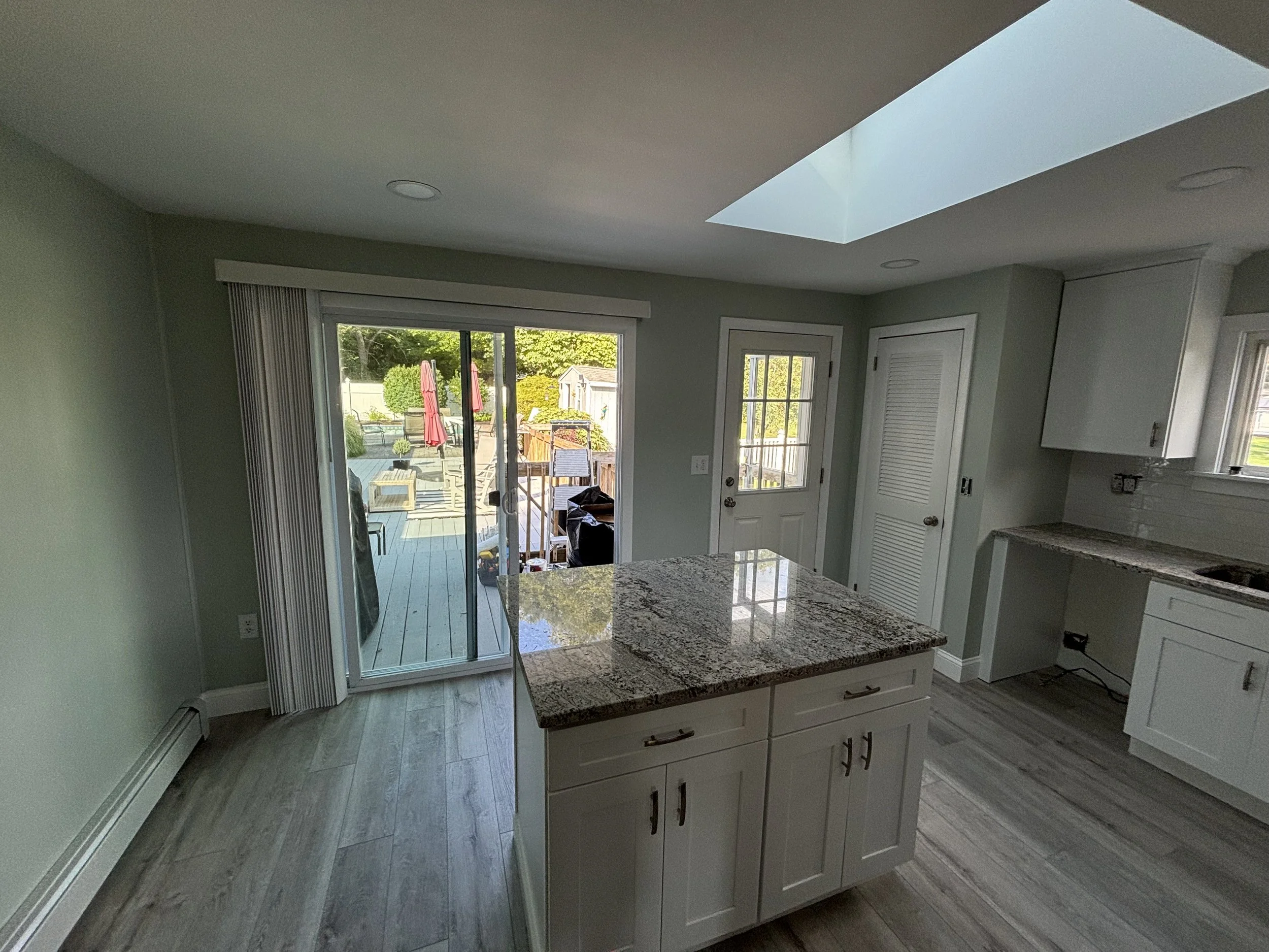 Modern kitchen renovation with white cabinets, stone countertops, natural lighting, and updated finishes.