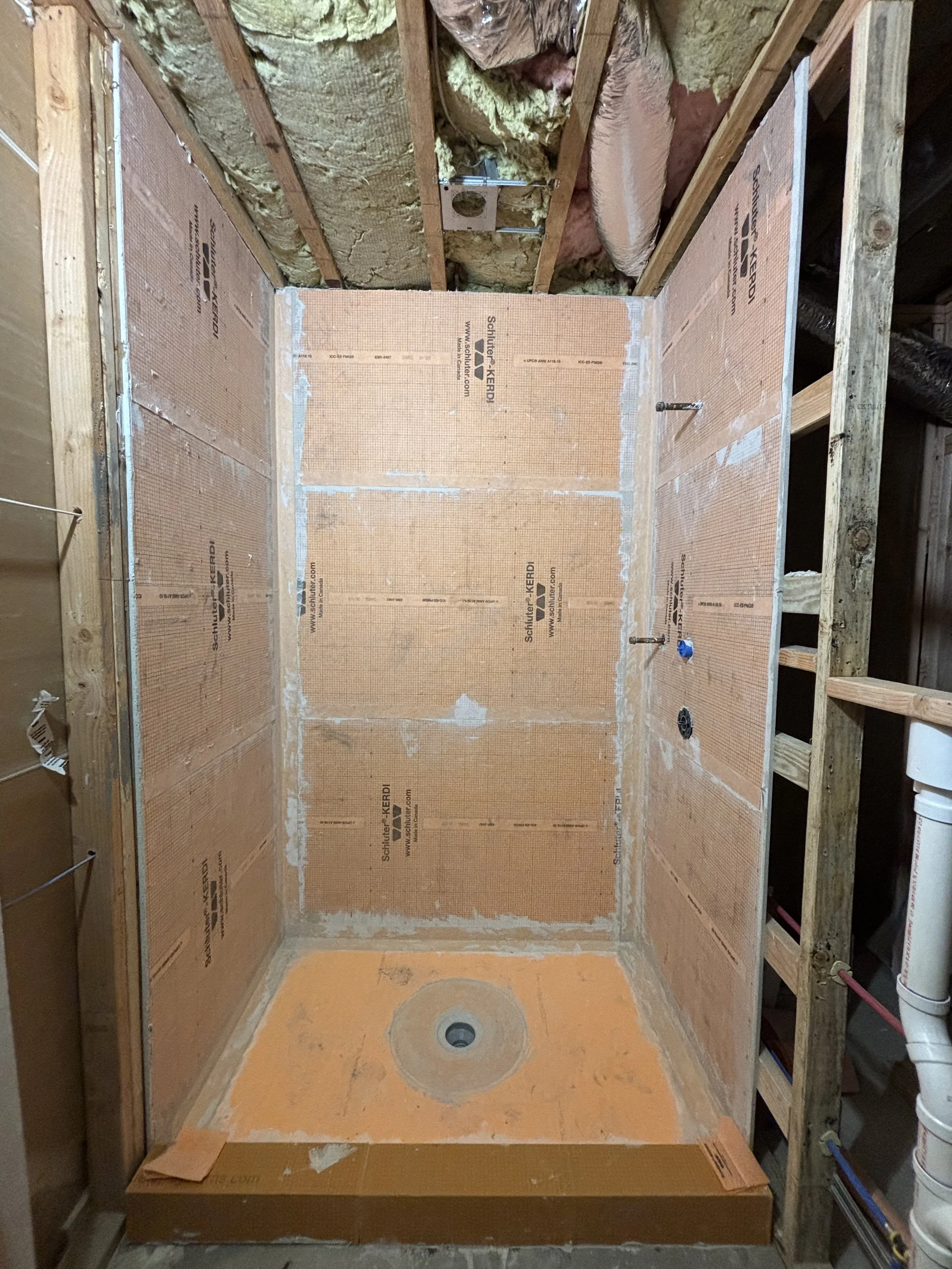 Bathroom renovation in progress with waterproof shower system, plumbing preparation, and tile installation.