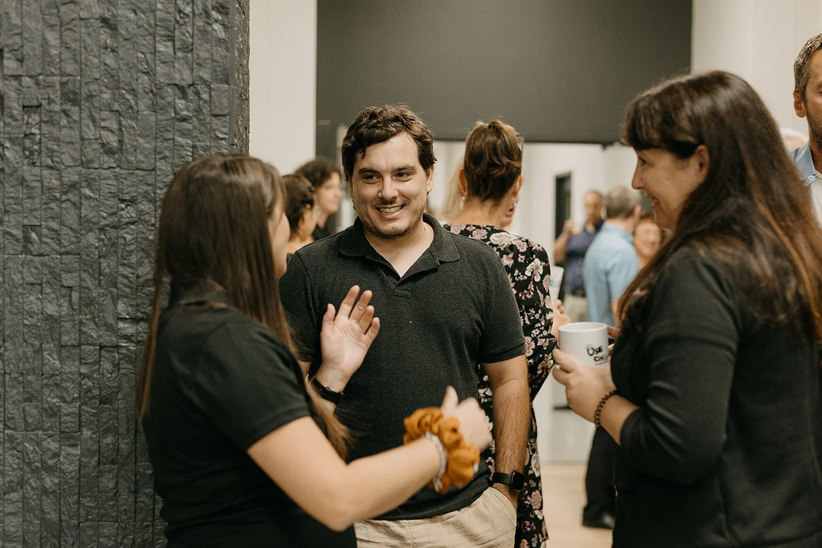 Un groupe de personnes en conversation et souriant, mettant à l'avant-plan le fondateur de l'agence, lors d'un événement social corporatif.