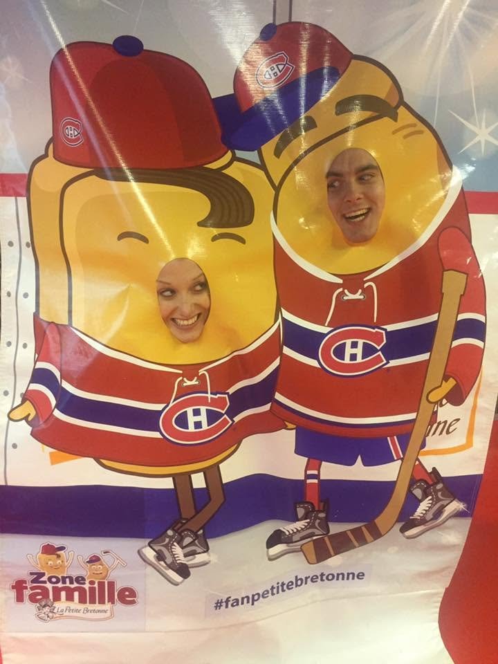 Deux personnes posent derrière une découpe en forme de pain au chocolat de la Petite bretonne, à l'effigie de l'équipe de hockey sur glace du Canadien de Montréal, avec leurs visages visible à travers trois trous dans la découpe.