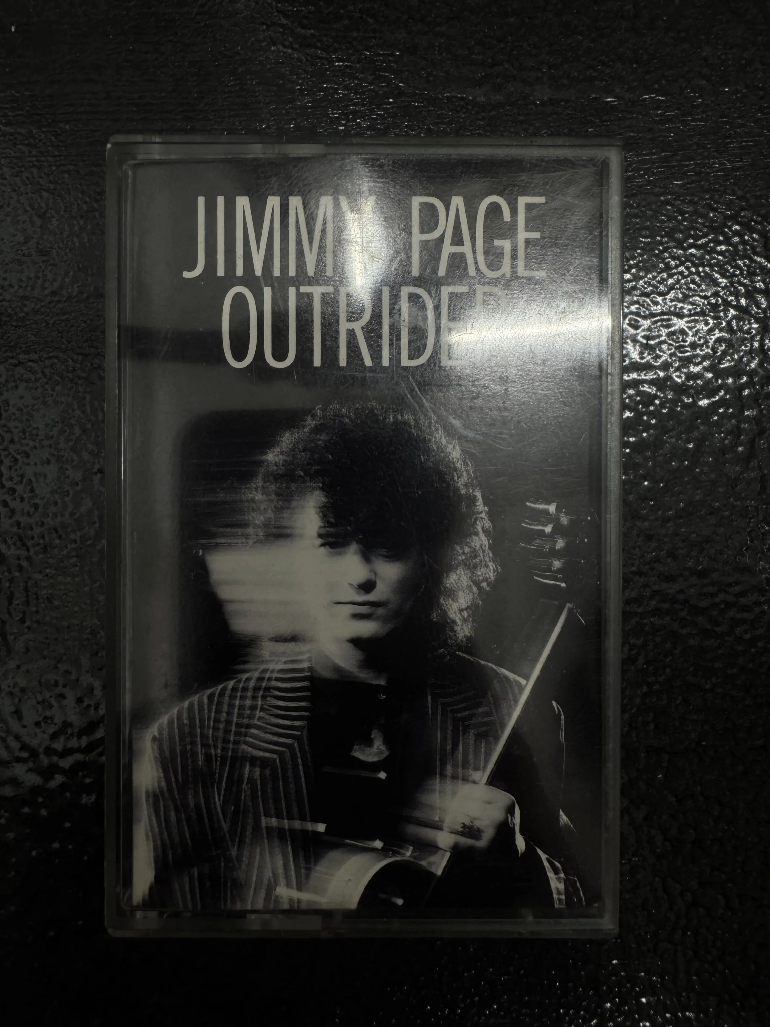 Jimmy Page Outrider cassette tape on a dark surface