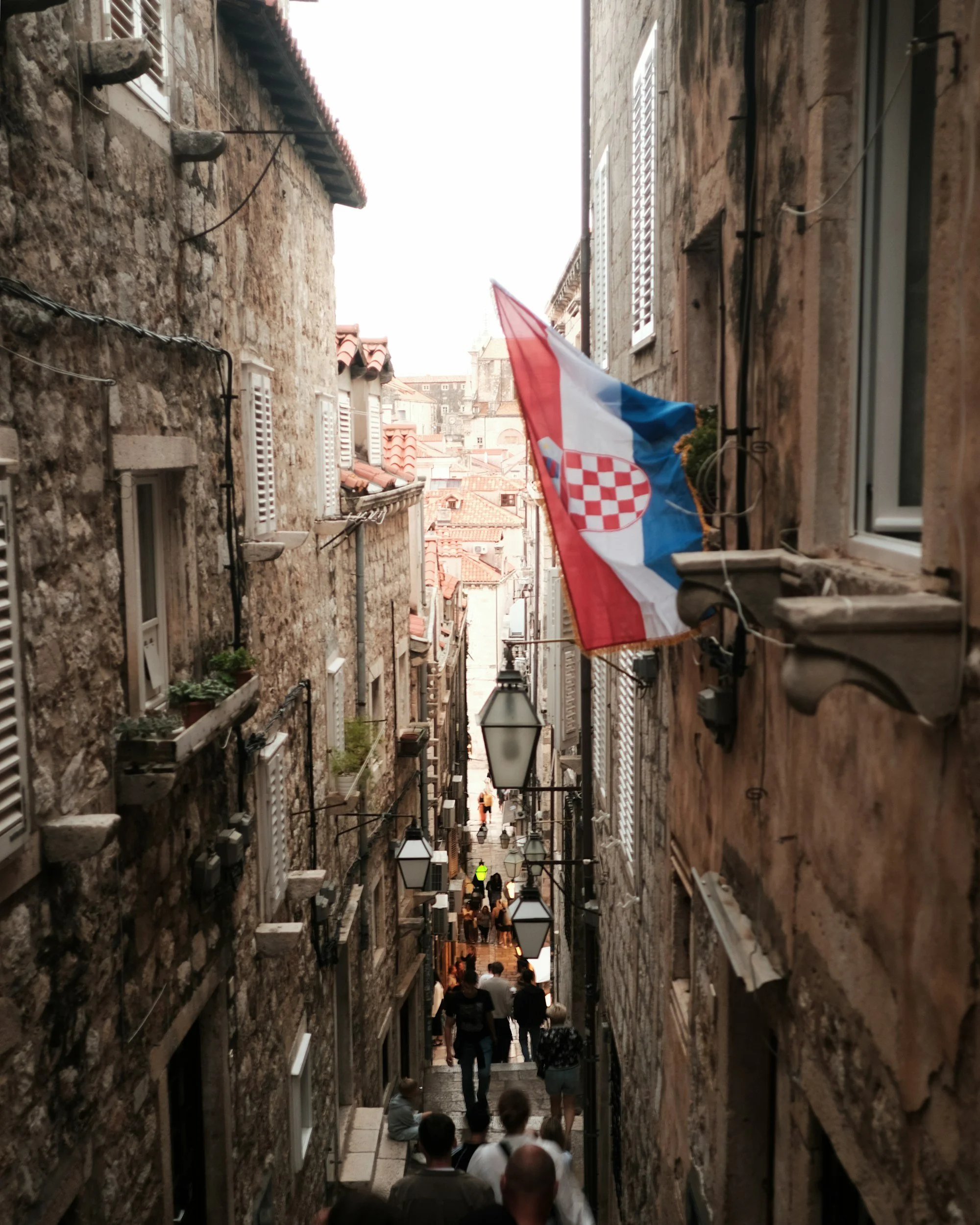 Narrow stone street in a Croatian old town with a Croatian flag.