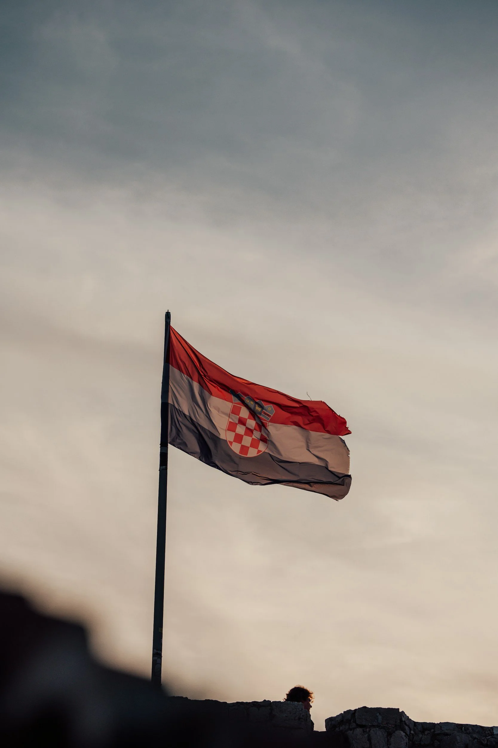 atian flag flying above historic stone ruins.