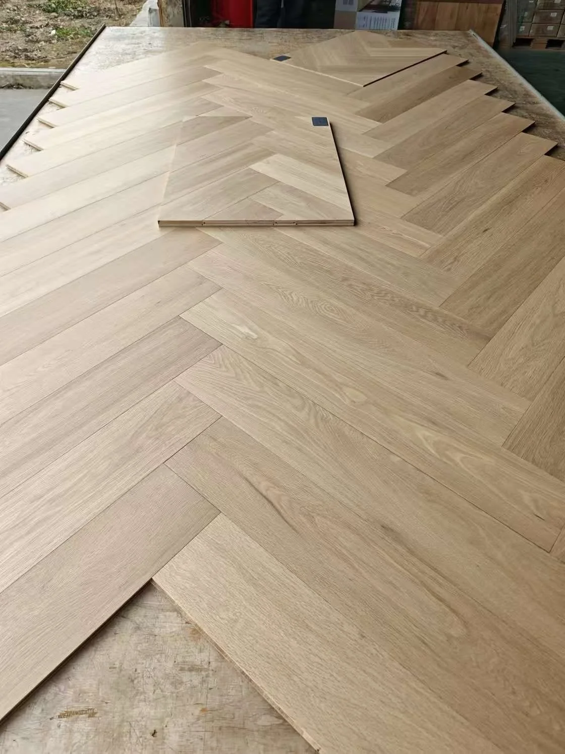 Multiple pieces of light-colored wooden flooring planks arranged in a pattern on a table.