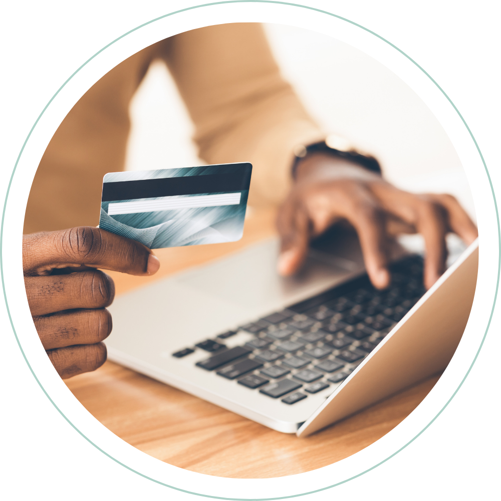 Person holding a credit card in front of a laptop keyboard.
