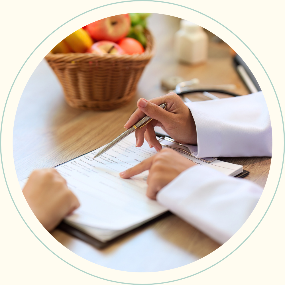 A healthcare professional filling out a form at a wooden table, with a basket of apples and a stethoscope nearby.