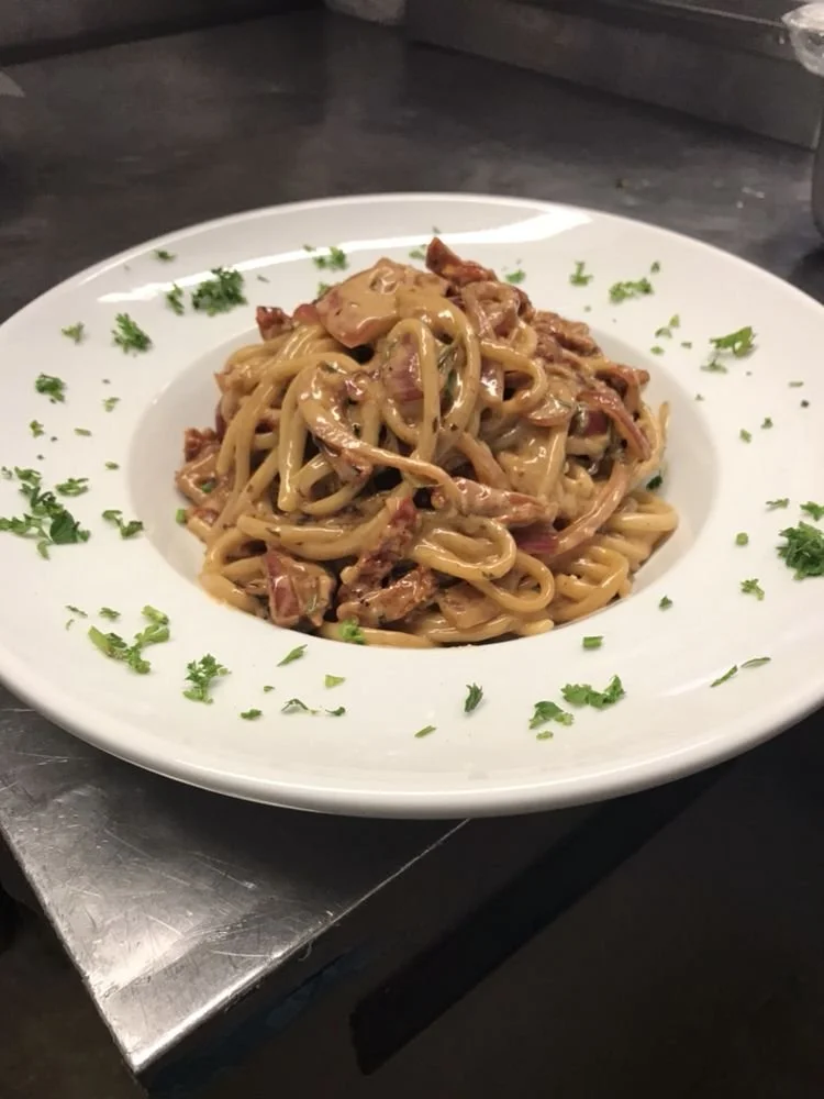 Plate of fettuccine pasta with a creamy sauce, garnished with chopped parsley.