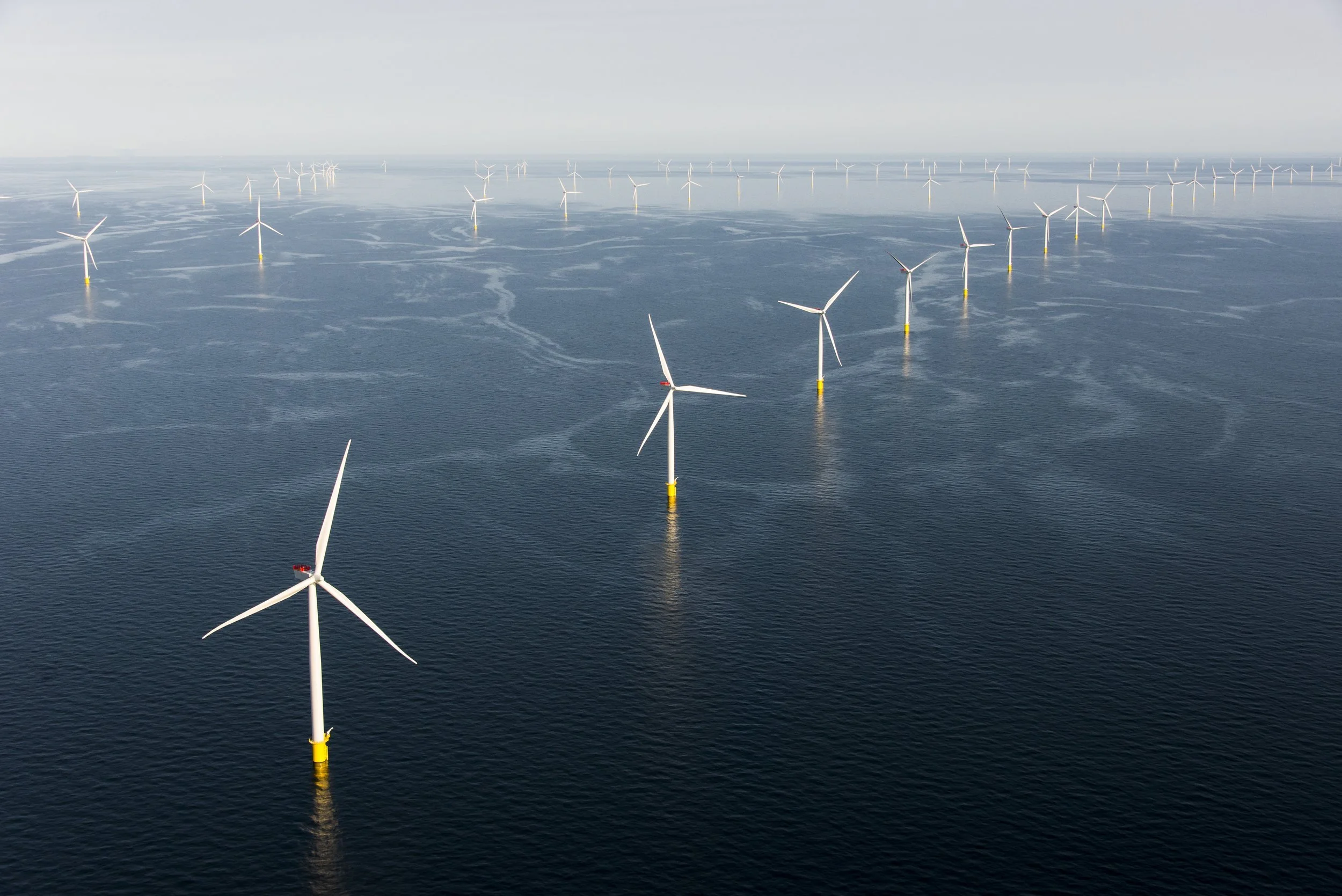 An aerial view of an offshore wind farm with multiple wind turbines installed in the ocean.
