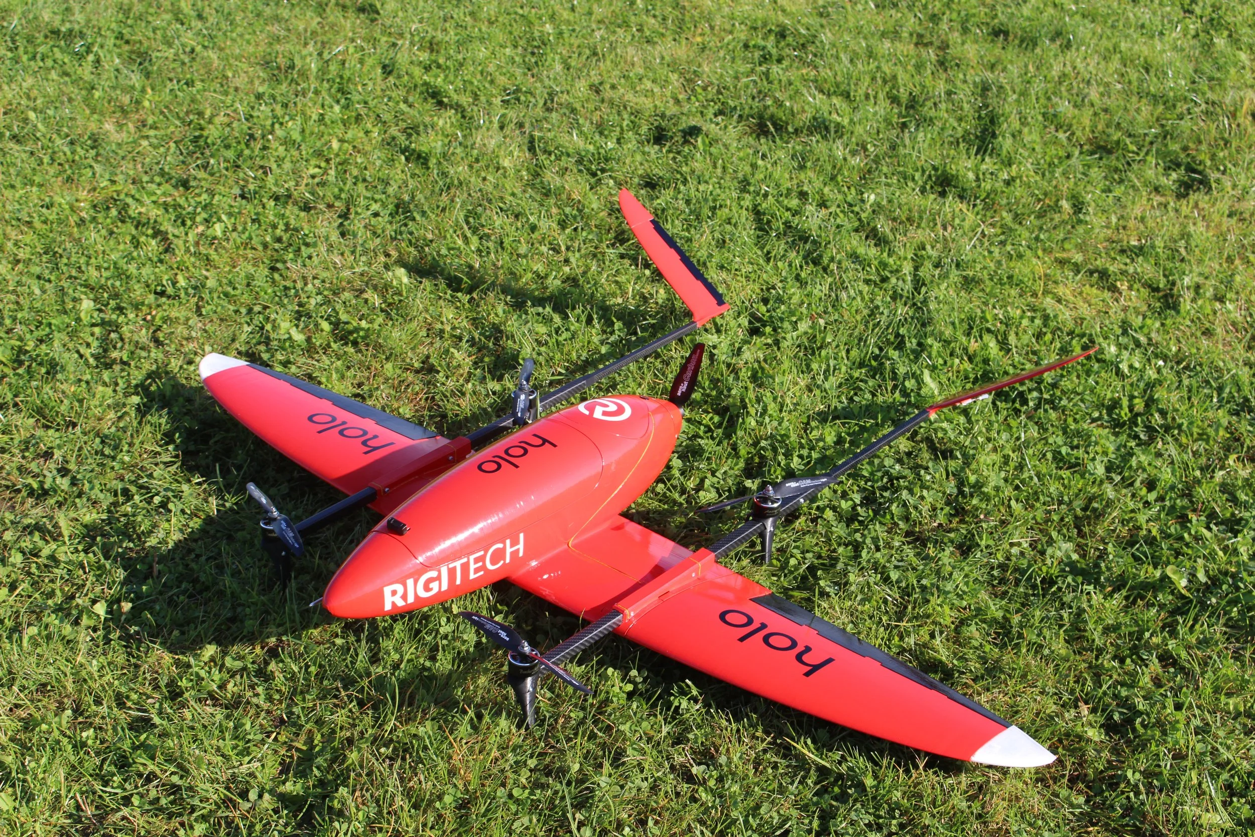 Red and black remote-controlled helicopter lying on green grass
