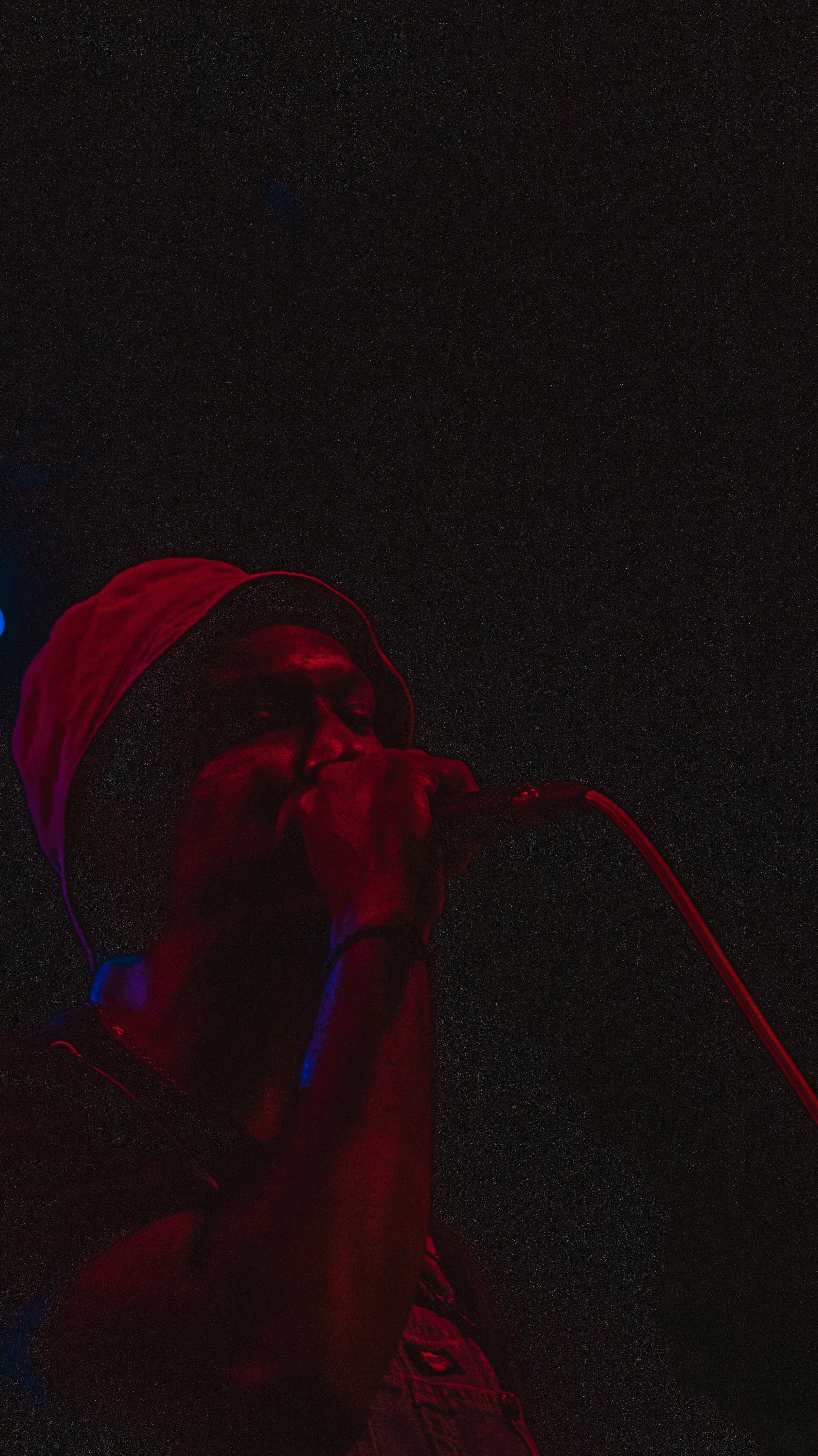 A man wearing a Santa hat is singing into a microphone against a dark starry night sky.