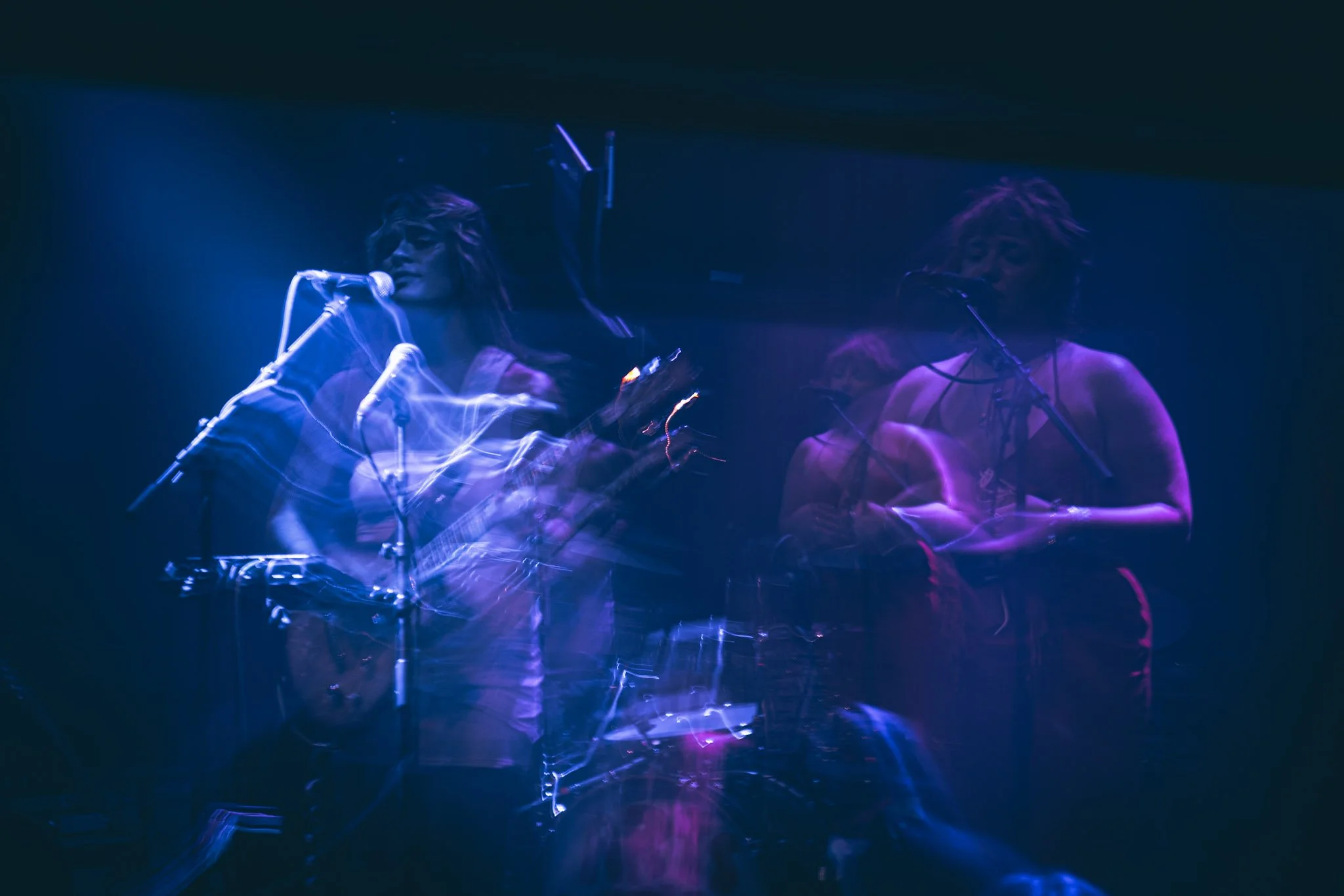 Two musicians performing on stage with purple and blue lighting, capturing movement and energy.