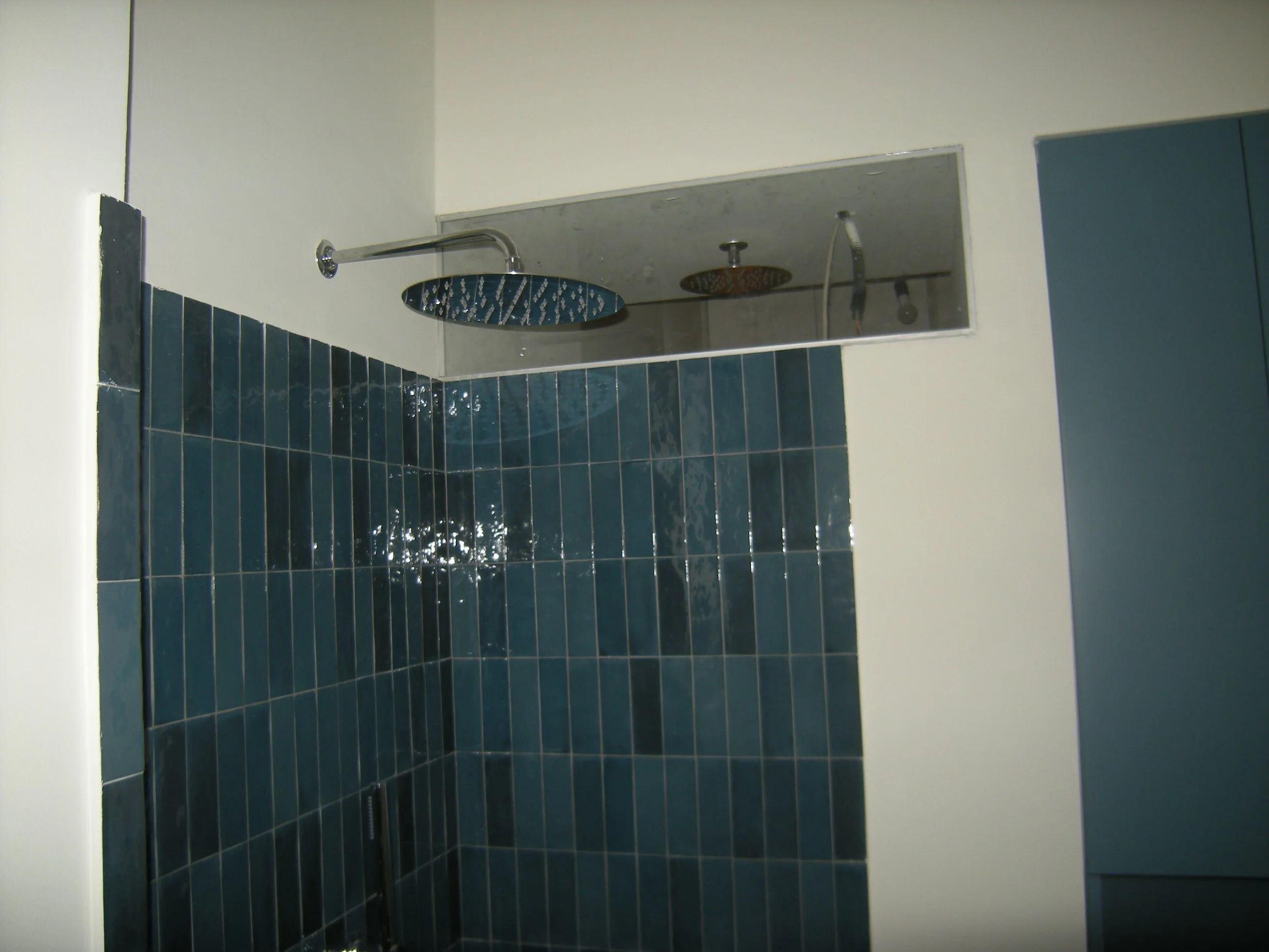 Doccia moderna con soffitto piatto e rivestimento di piastrelle blu scuro.