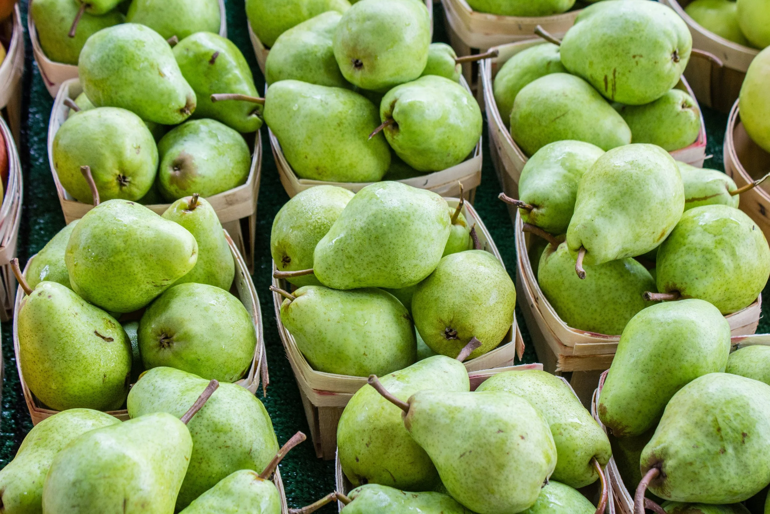 Green pears in small baskets at a market.