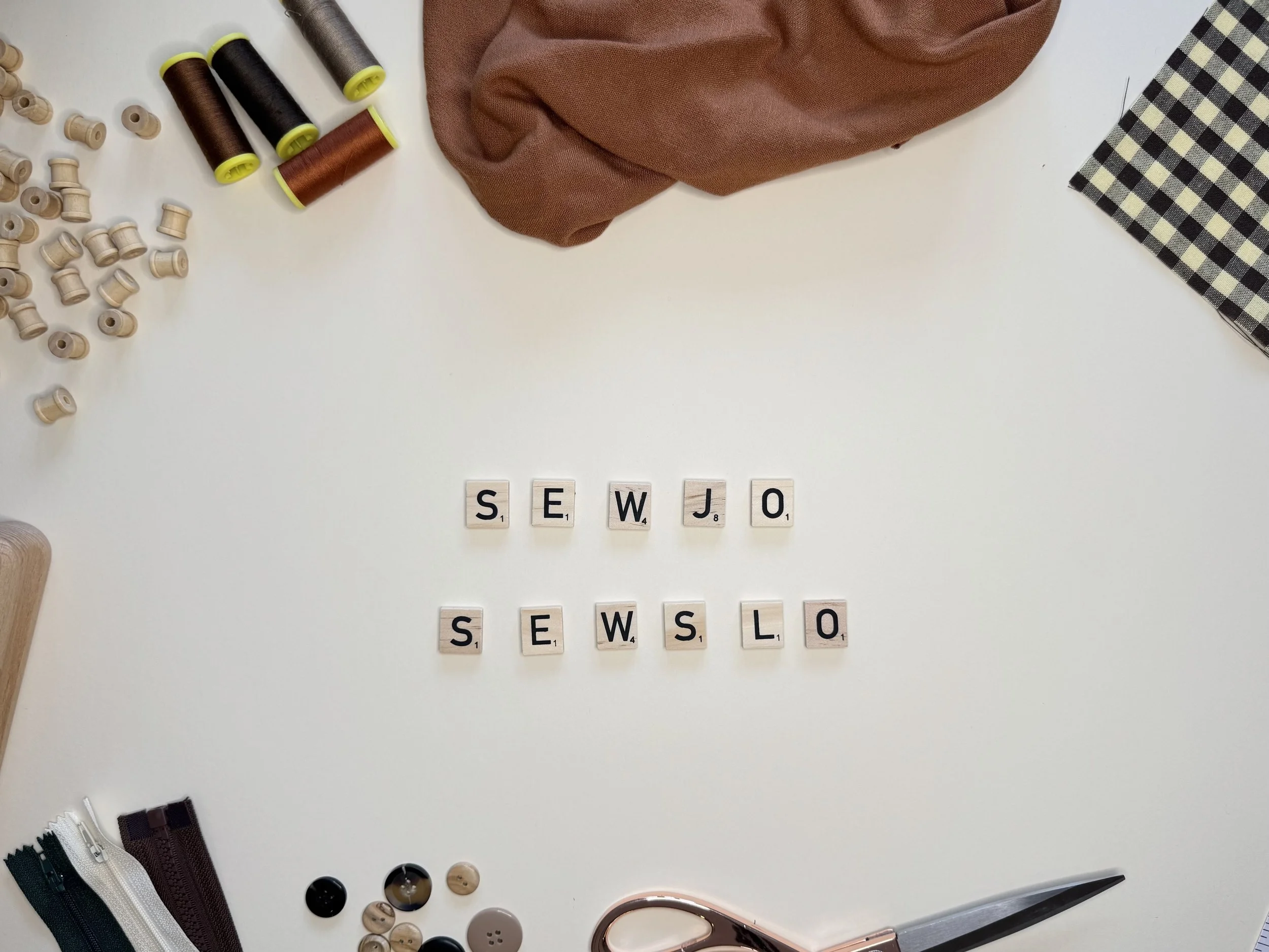 Fabric, thread spools, buttons, and scissors arranged around the SewJo SewSlo name
