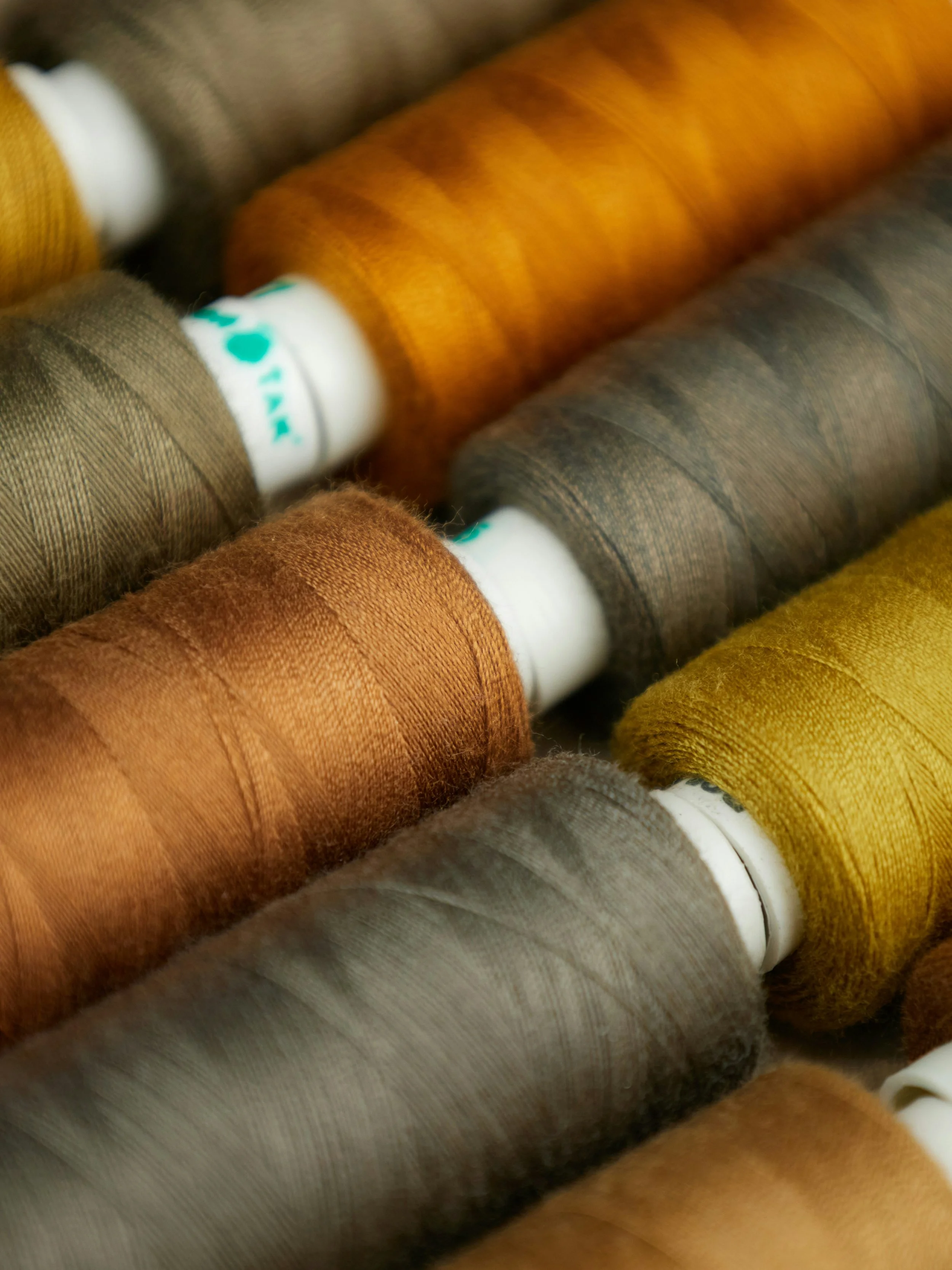 Spools of thread in warm brown, green, and neutral colours.