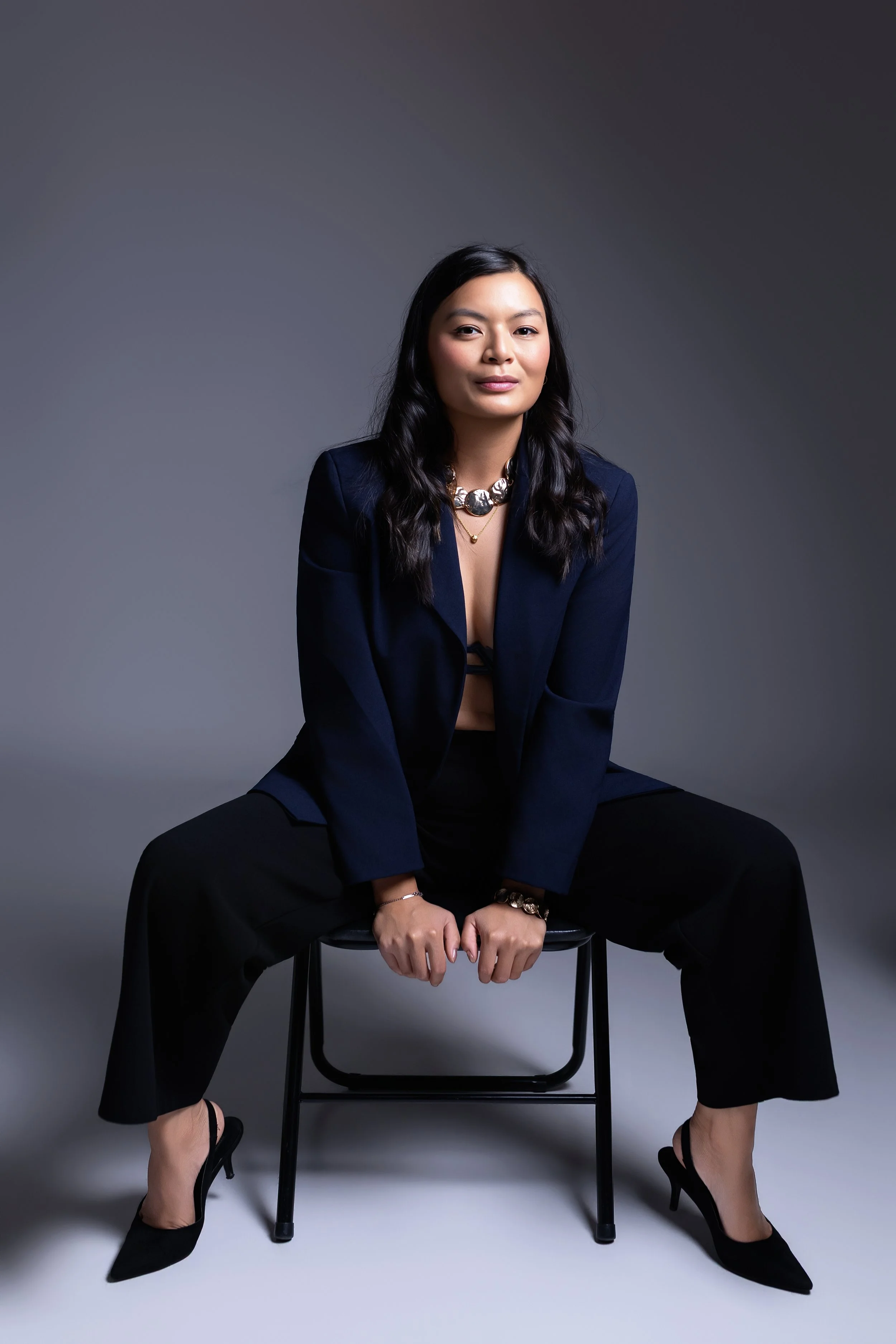 Kvinne med langt mørkt hår i marineblå blazer – elegant studioportrett