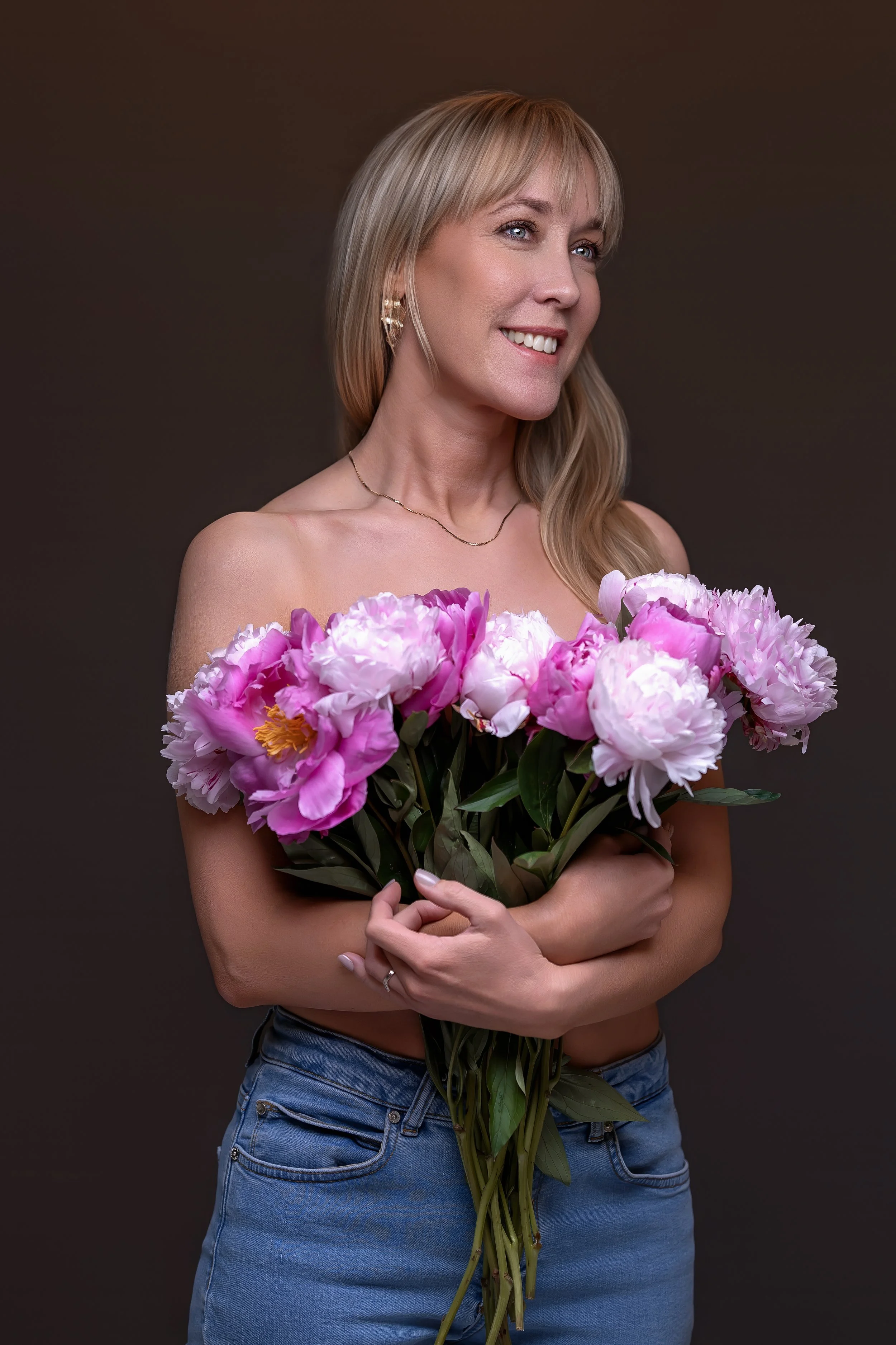 Smilende kvinne med stor bukett rosa peoner – kvinnefotografering i studio i Oslo