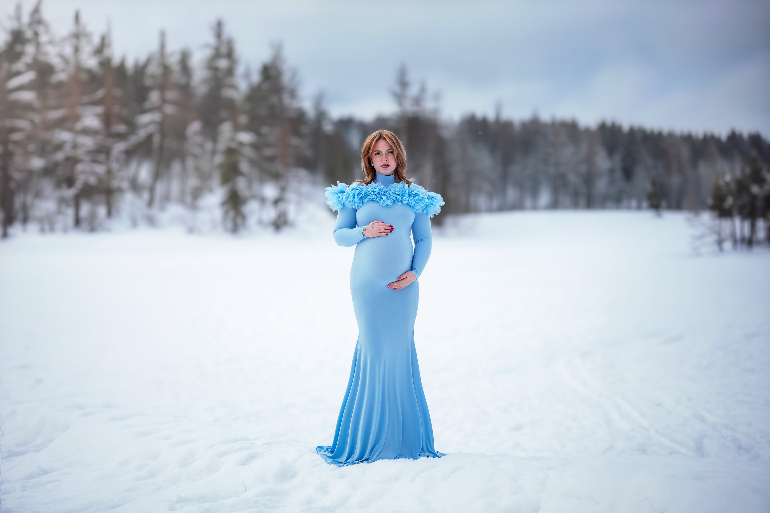 Kvinne i lang blå kjole med volanger – elegant gravidfotografering i Oslo