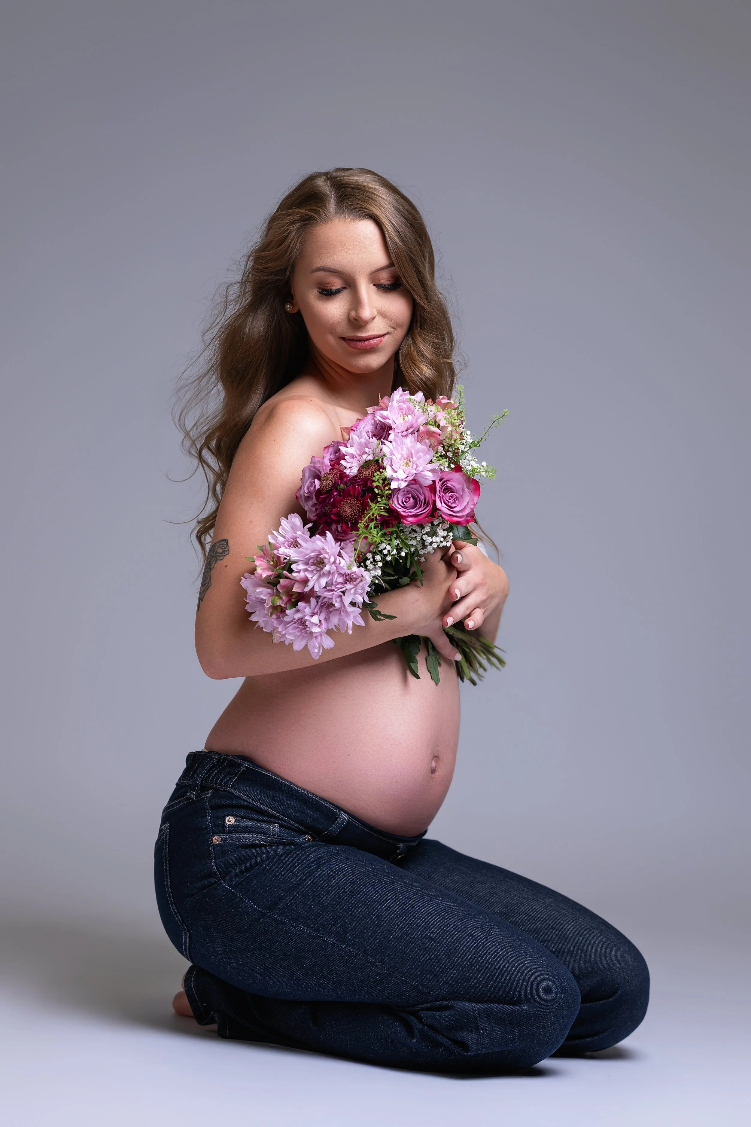 Gravid kvinne med langt brunt hår på kne – gravidfotografering i studio i Oslo