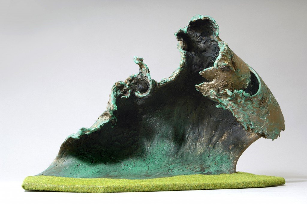 Rearing wave by Maggi Hambling. Sculpture maquette resembling a crashing ocean wave, mounted on a grassy base.