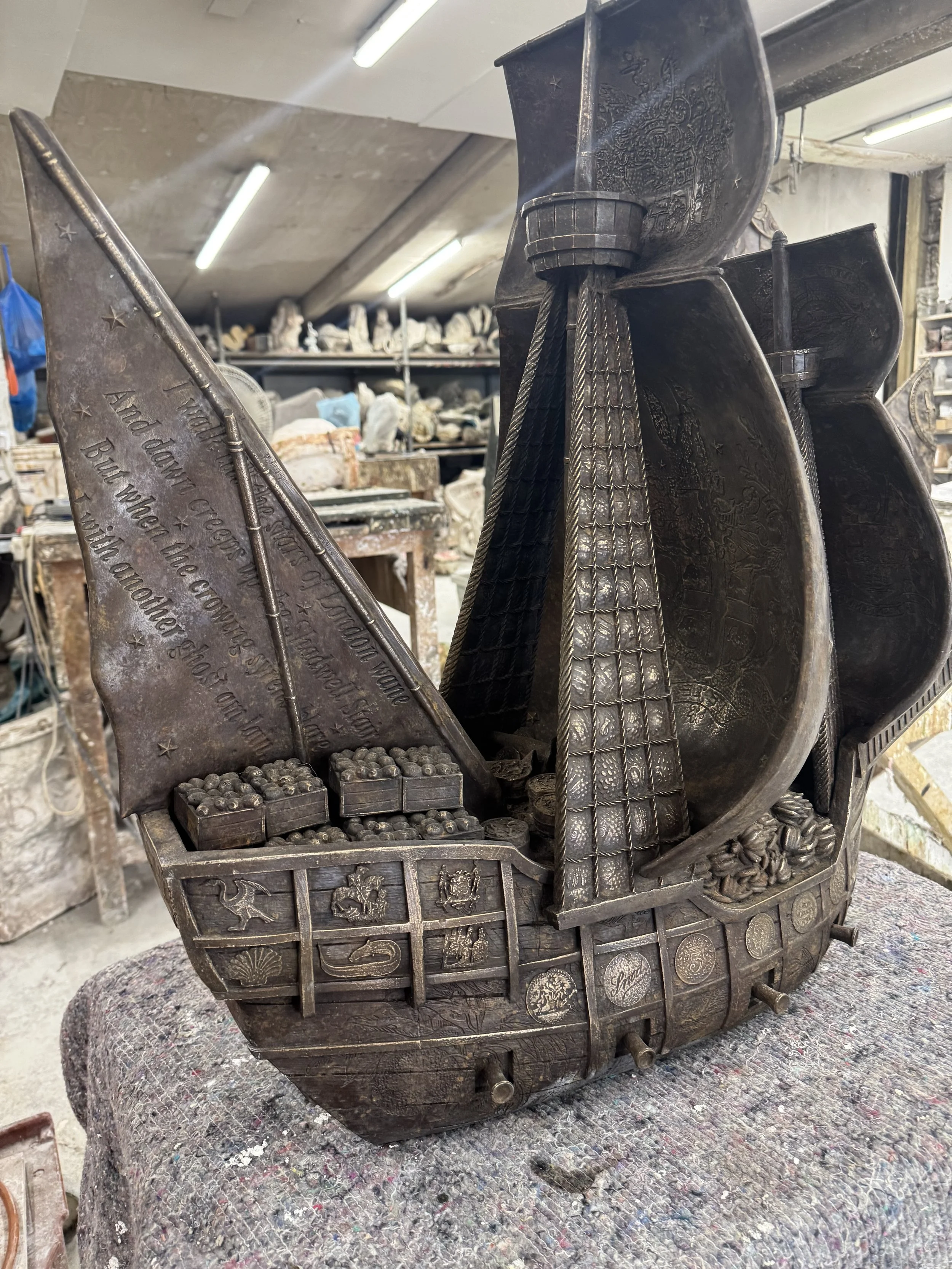 Hew Locke bronze boat sculpture from Cargoes at Arch Bronze, showing a tall patterned sail and loaded deck.