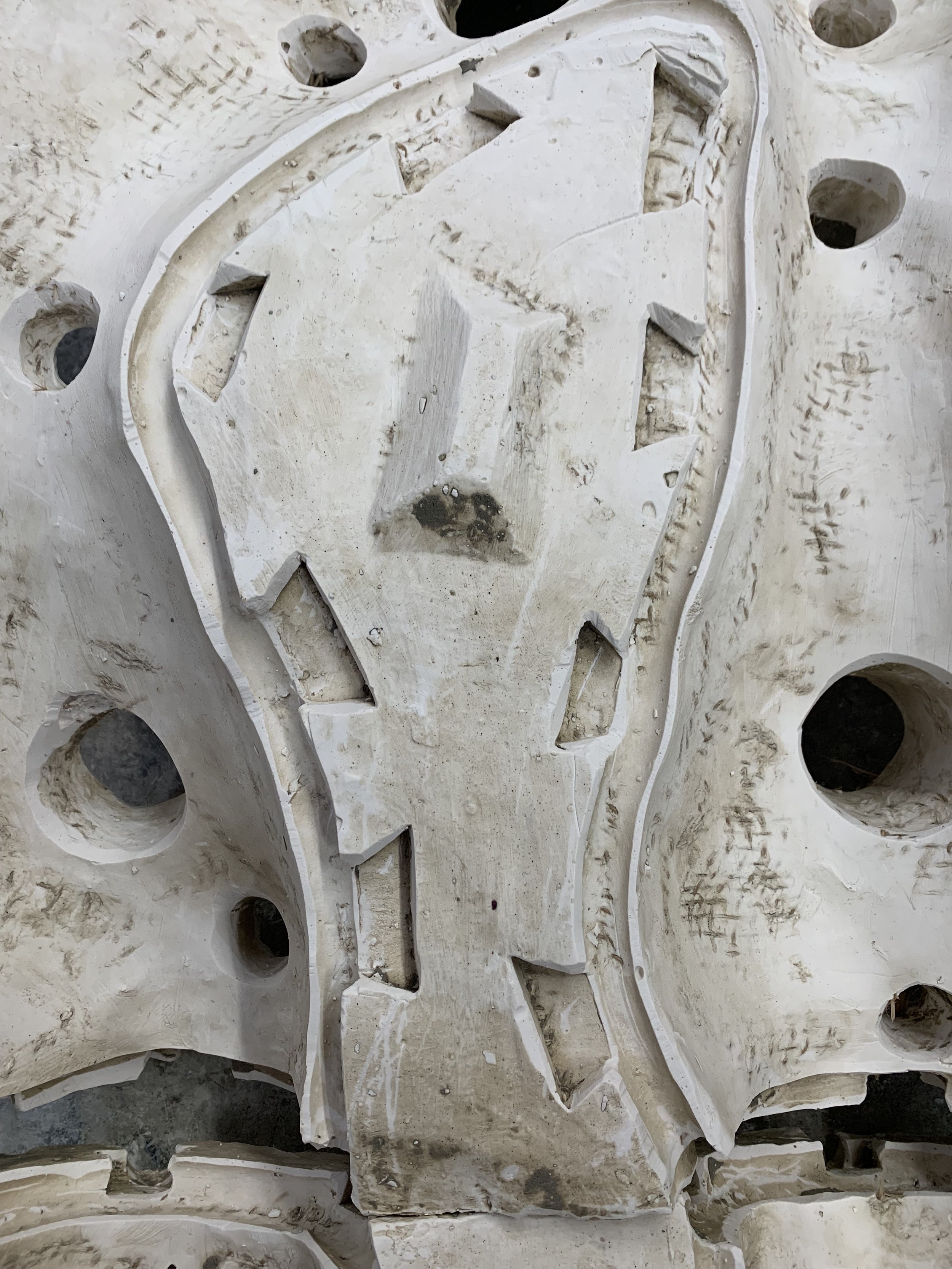 Close-up of a plaster surface with various holes and indentations, part of a plaster mould.
