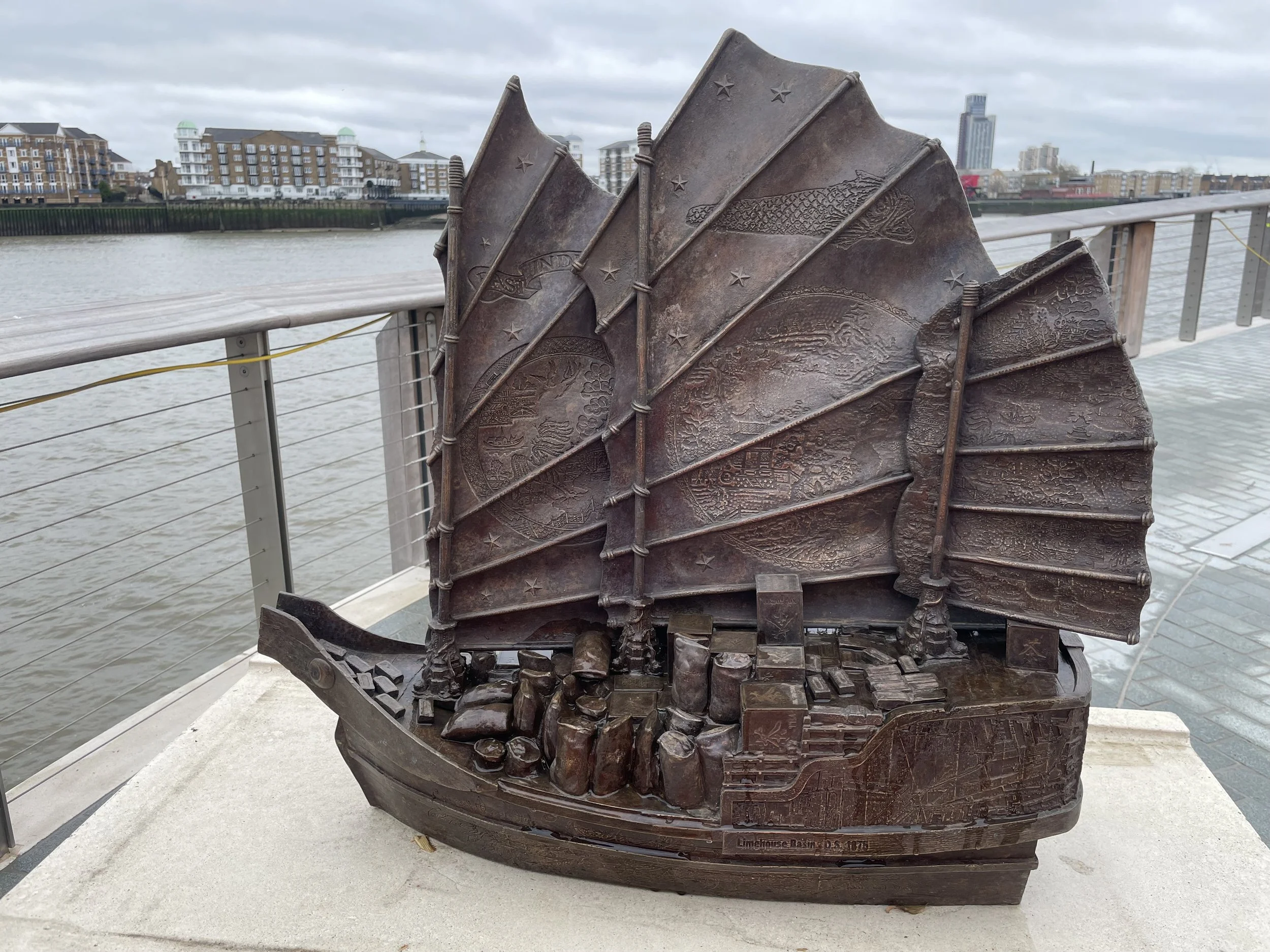 Close view of a Hew Locke Cargoes bronze boat installed beside the Thames at King Edward Memorial Park.