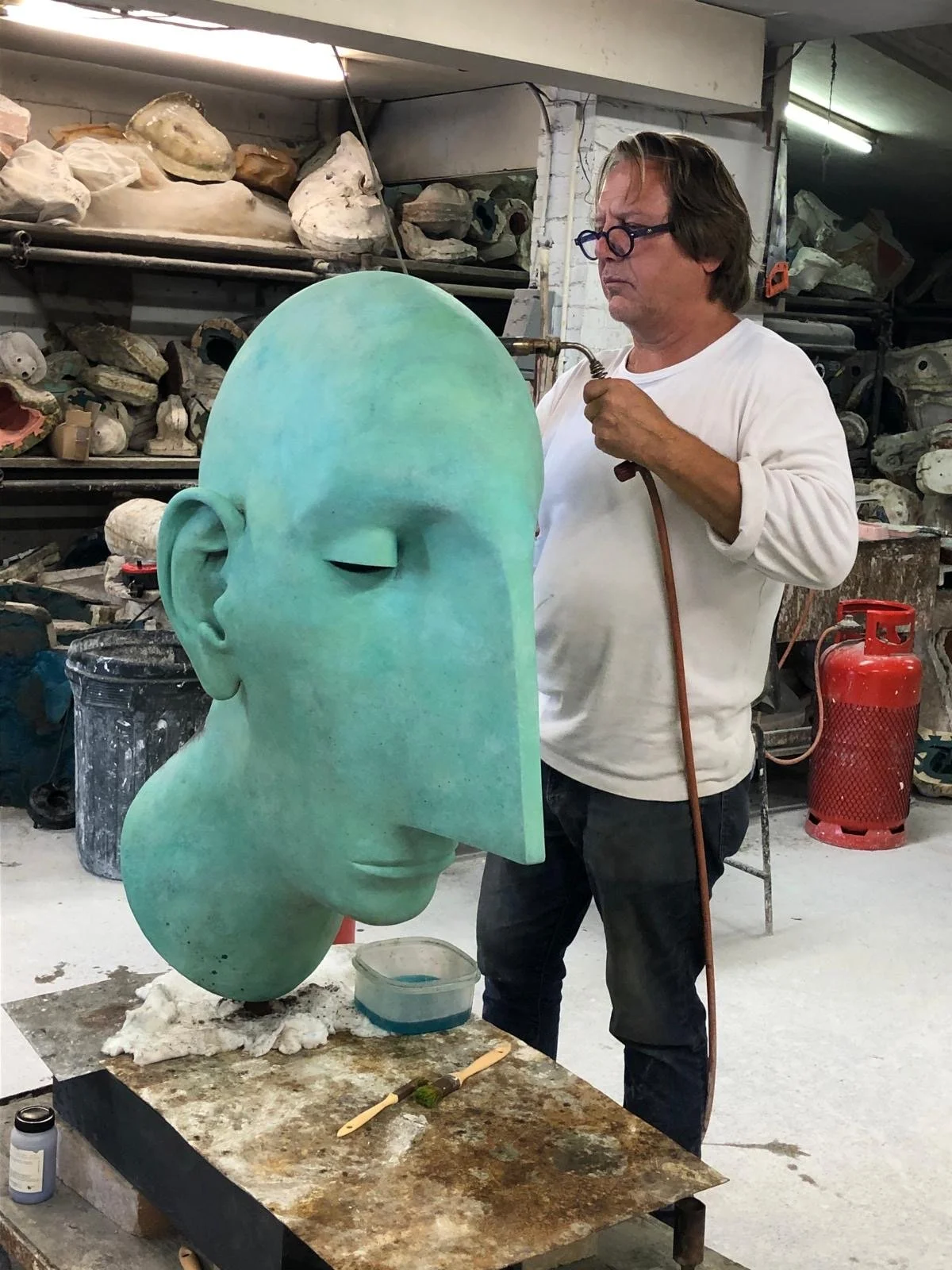 Patination being applied to a large bronze head at Arch Bronze.