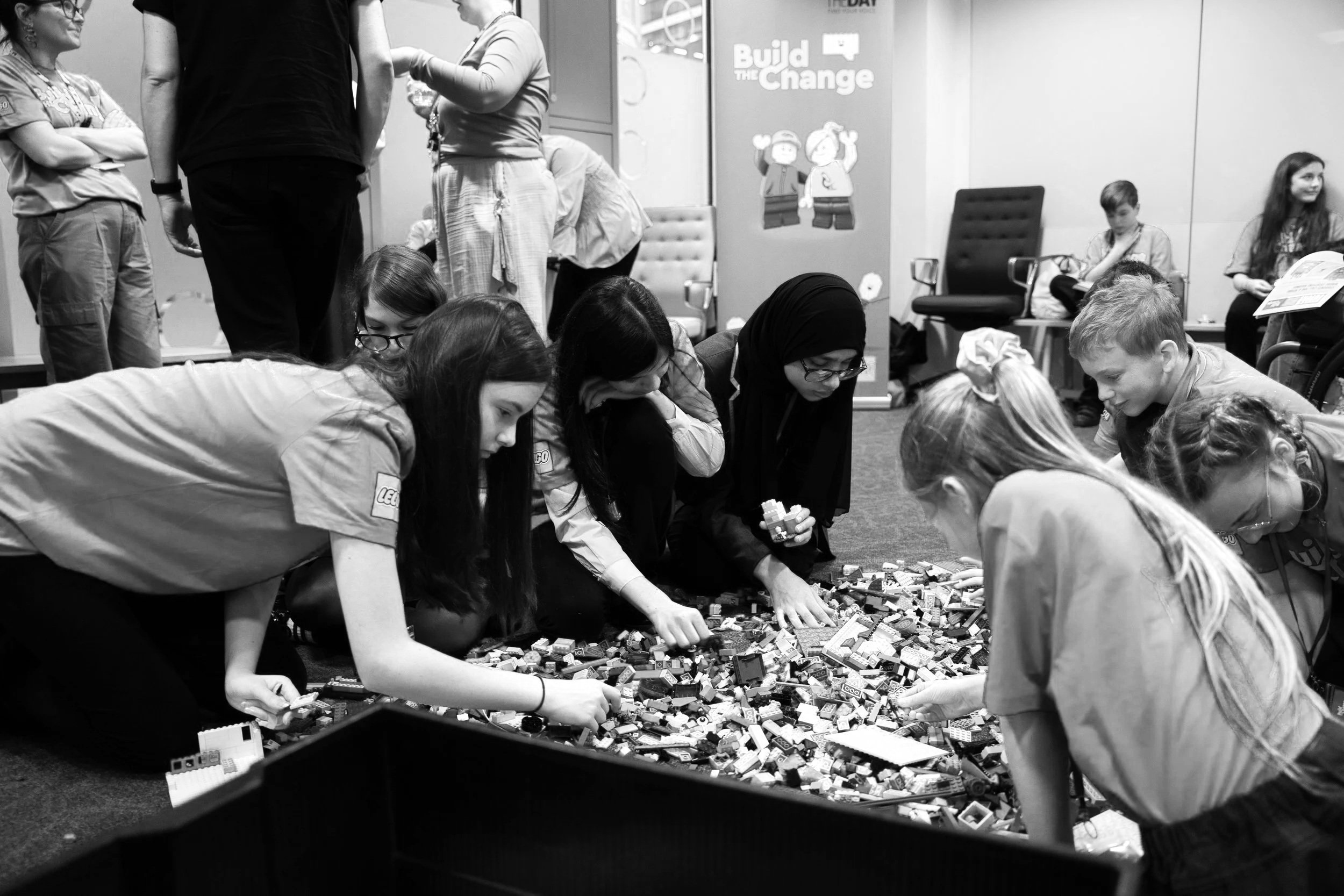 Black & white photo of students building with bricks at a LEGO Build the CHange Youth Council event.